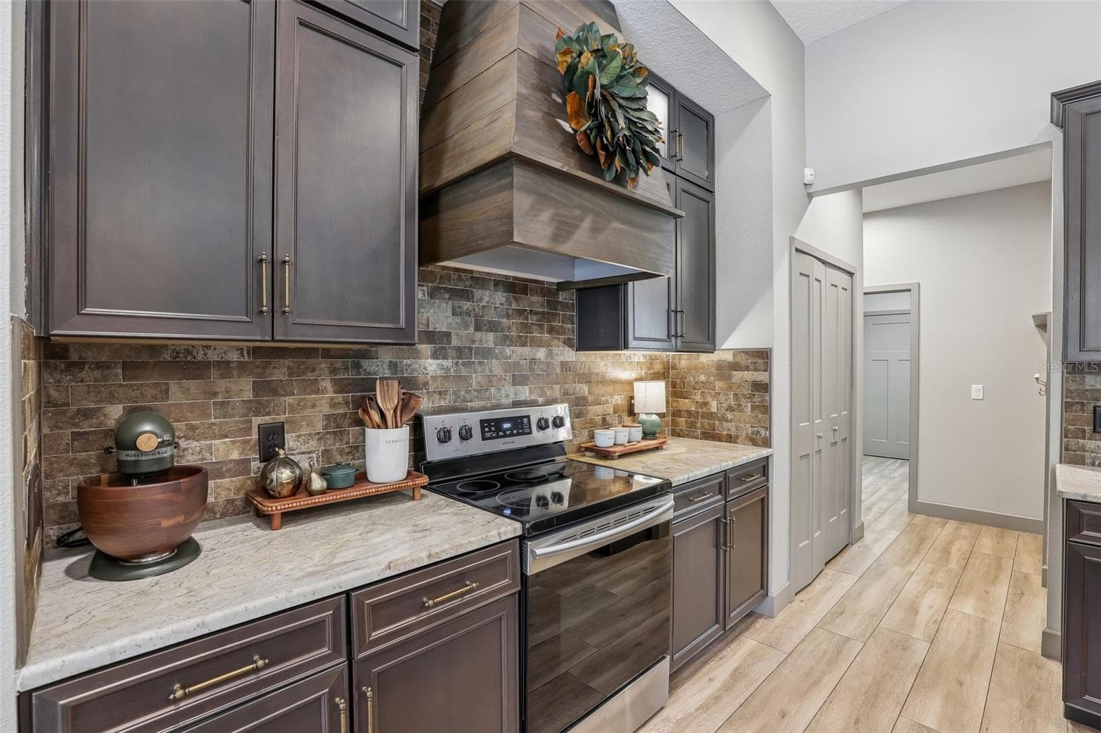 The Kitchen is truly a CHEF'S DREAM, featuring an abundance of cabinetry and counter space, STAINLESS STEEL APPLIANCES, a striking BRICK BACKSPLASH, stylish range hood, generous island with BREAKFAST BAR SEATING and a convenient pantry closet. - 19179 SABAL ST, ORLANDO