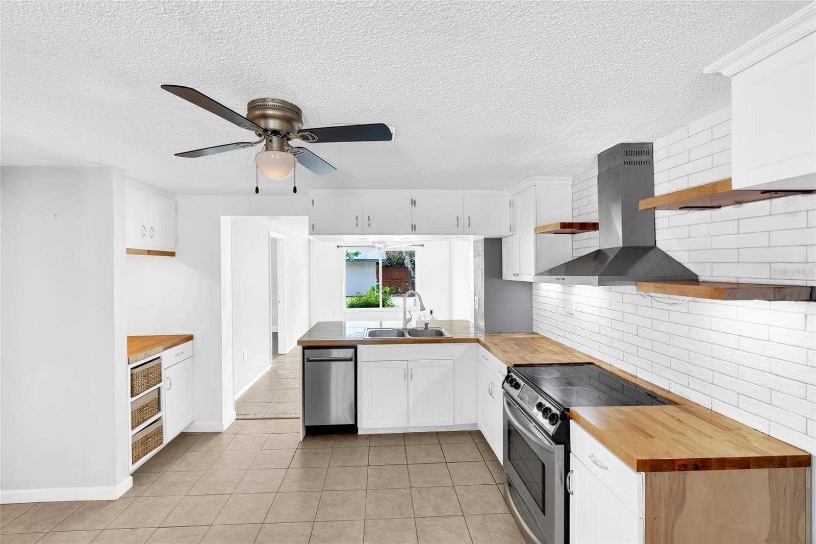 The updated kitchen features white cabinetry, butcher block countertops, stainless steel appliances and a clean subway tile backsplash. - 142 2ND AVE, NOKOMIS