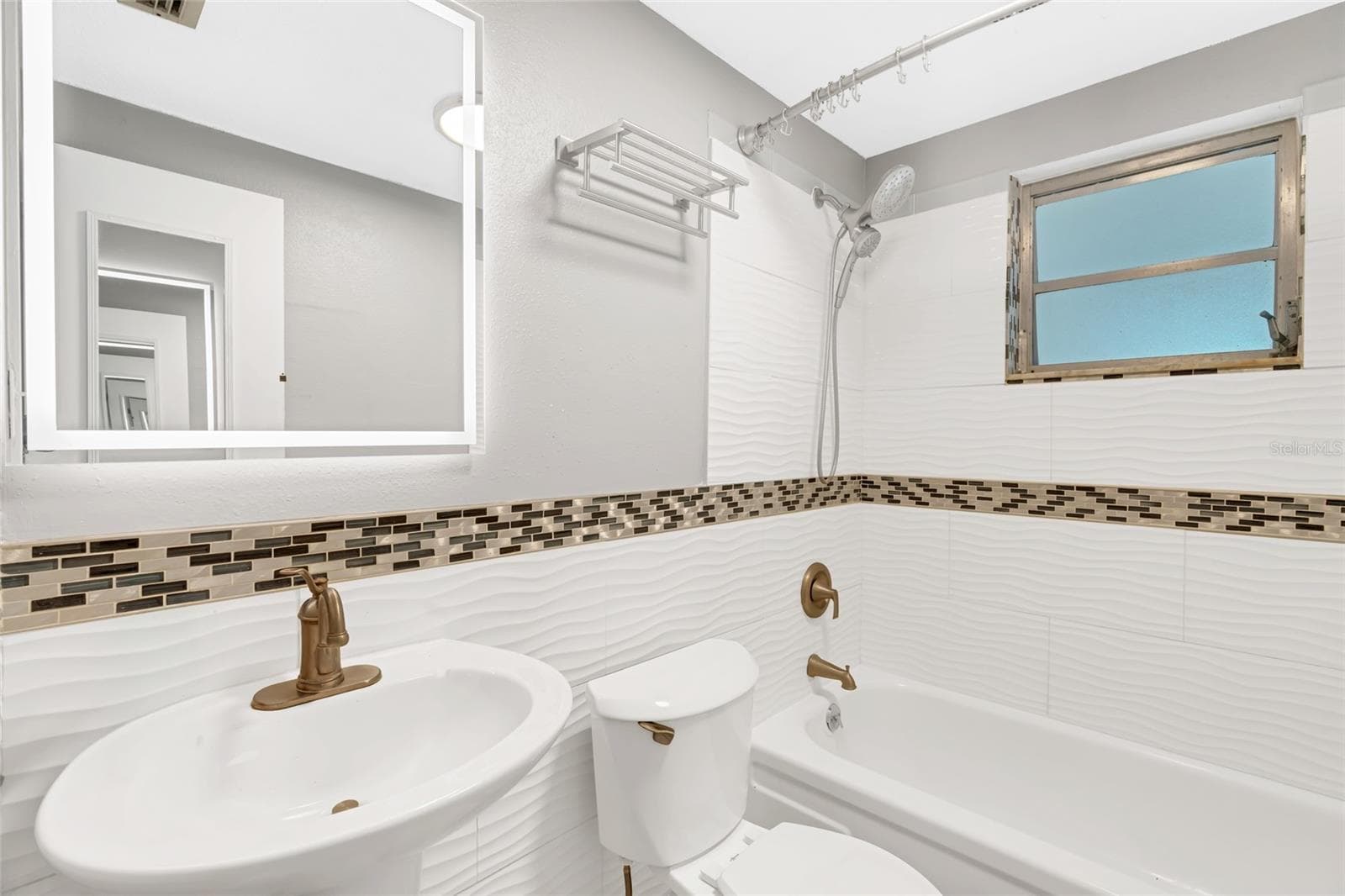 The guest bath includes a tub and shower combination, updated tile and a lighted mirror. - 142 2ND AVE, NOKOMIS
