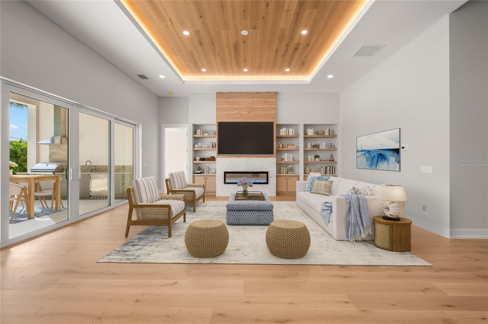 Virtually staged family room featuring a modern fireplace and custom built-ins, opening seamlessly to the outdoor entertaining area. - 3360 BAYOU SOUND, LONGBOAT KEY