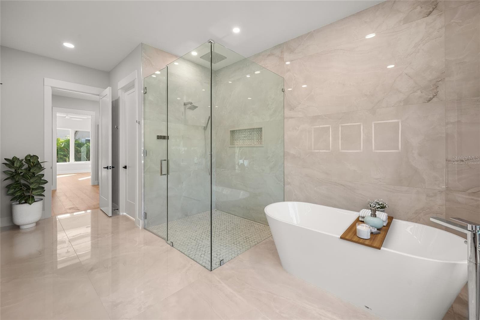 Virtually staged primary suite features a luxurious spa-inspired bath with soaking tub, spacious walk-in shower, designer tile, beautifully curated finishes, and a generous walk-in closet. - 3360 BAYOU SOUND, LONGBOAT KEY