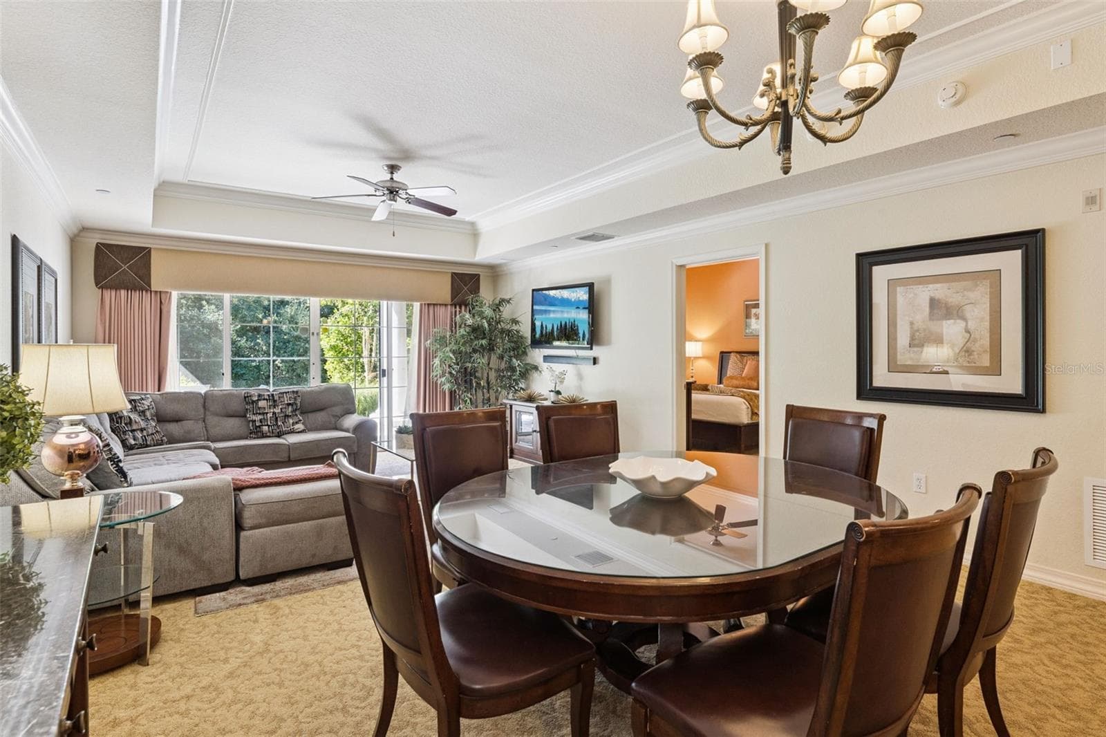 Dining Area: Dedicated dining space featuring an overhead chandelier, tray ceiling detailing, and an easy flow into the adjacent living room and bedroom hall. - 7656 WHISPER WAY #102, REUNION