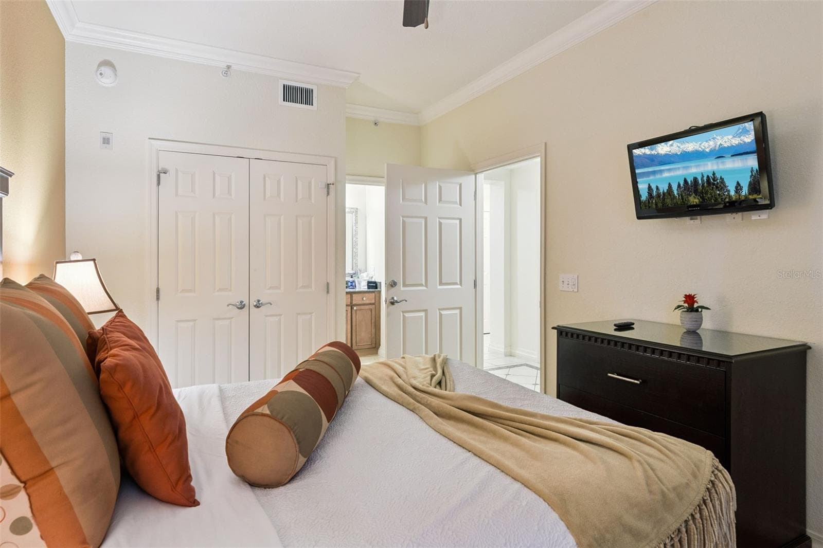 Bedroom: Comfortably sized bedroom offering crown molding, a wall-mounted flat-screen TV, double bi-fold closet doors, and direct access to a nearby bath. - 7656 WHISPER WAY #102, REUNION