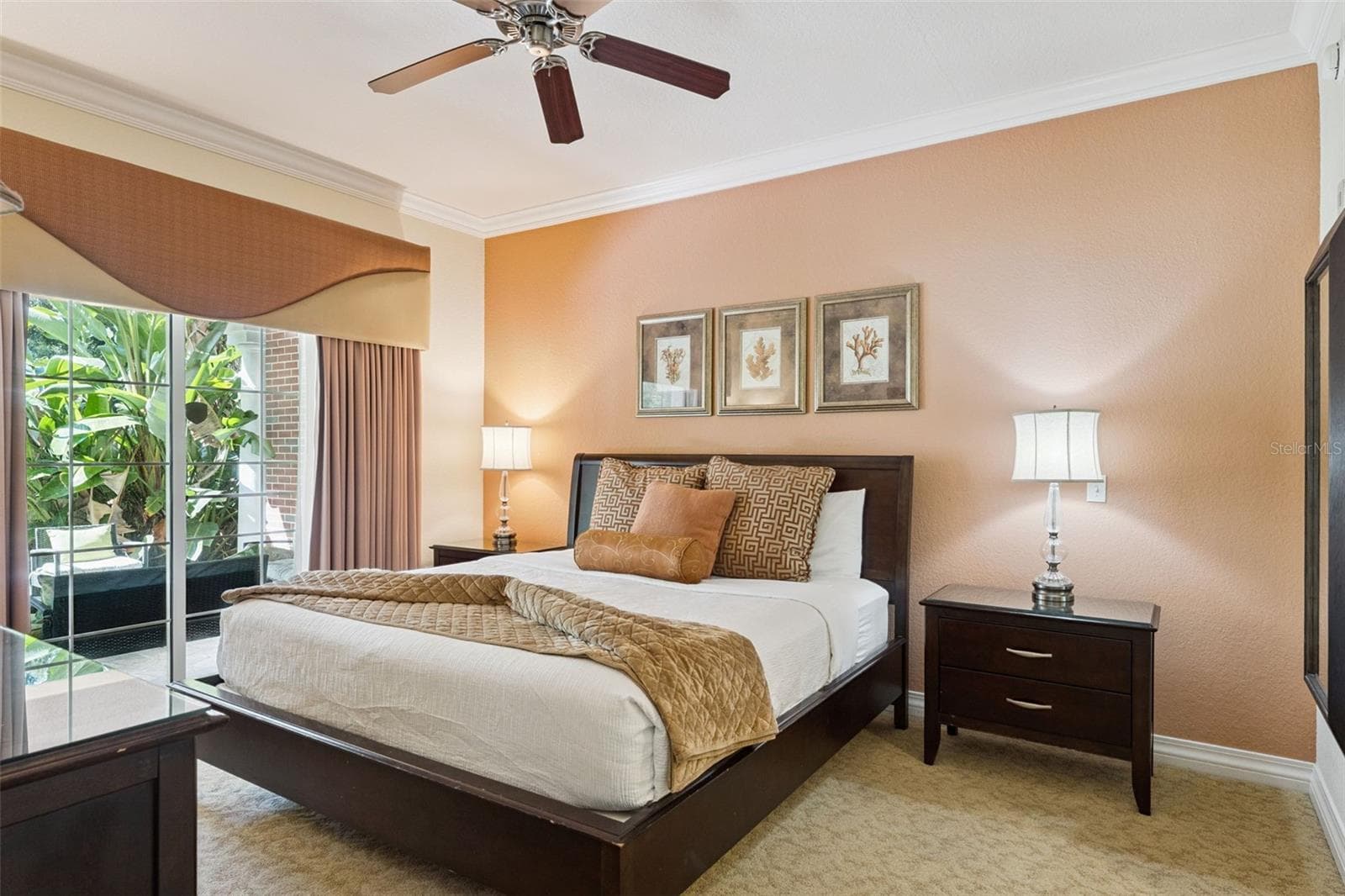 Primary Bedroom Alternate View: Primary suite showcasing a warm-toned accent wall, ceiling fan, nightstand space, and floor-to-ceiling glass sliders for convenient outdoor access. - 7656 WHISPER WAY #102, REUNION