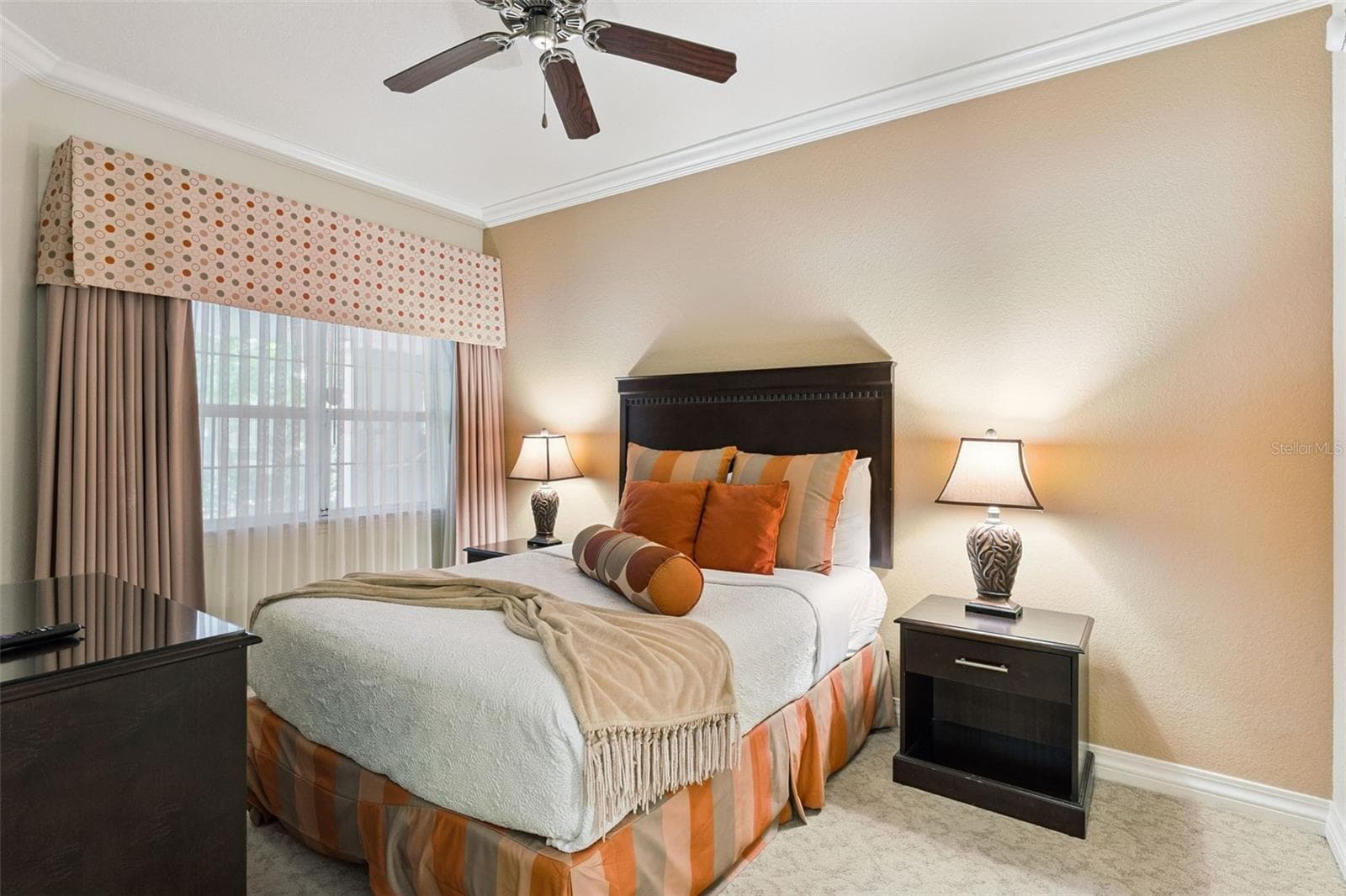 Guest Bedroom: Cozy guest bedroom complete with crown molding, a ceiling fan, dark wood furnishings, decorative window drapery, and warm neutral accent walls. - 7656 WHISPER WAY #102, REUNION