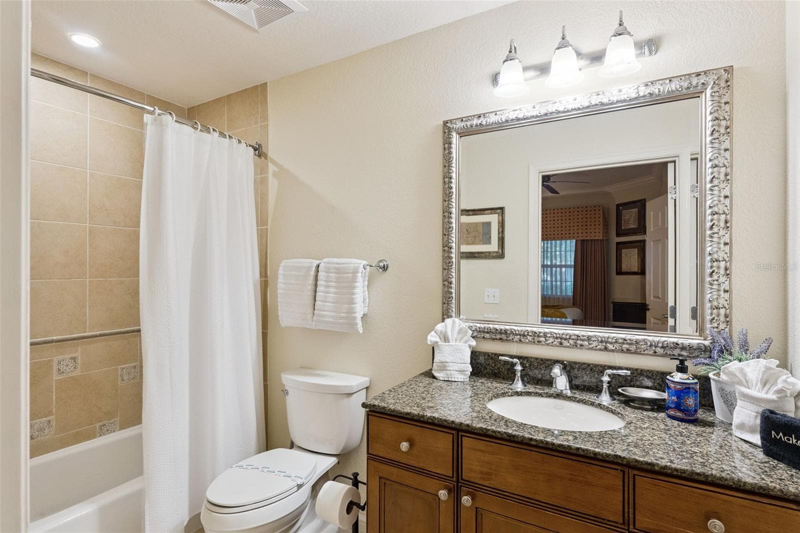 Additional Guest Bath: Well-maintained full bathroom offering a granite-topped vanity, framed mirror, multi-bulb lighting, and tub/shower enclosure. - 7656 WHISPER WAY #102, REUNION