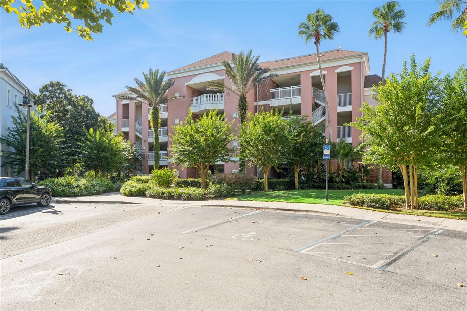 Parking & Grounds: Convenient marked parking spaces steps from the building entrance with vibrant landscaping and palm tree accents. - 7656 WHISPER WAY #102, REUNION
