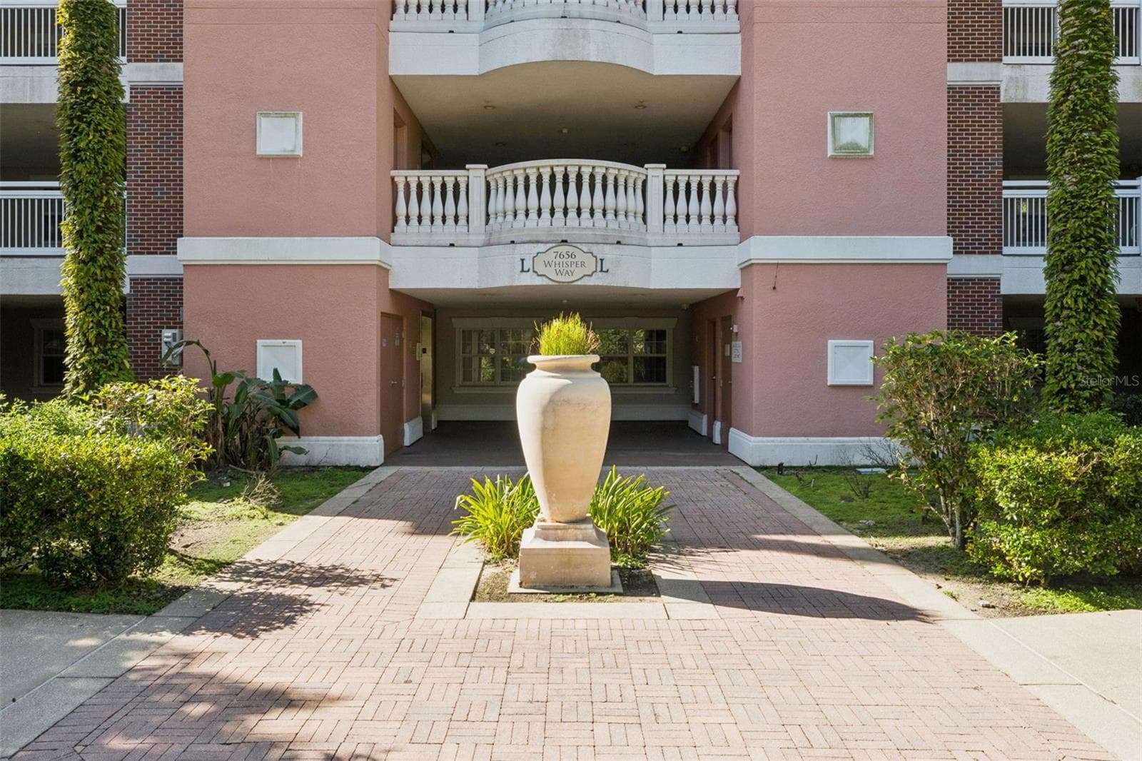 Building Entrance: Brick paver walkway and decorative urn planter leading into the covered building entrance. - 7656 WHISPER WAY #102, REUNION