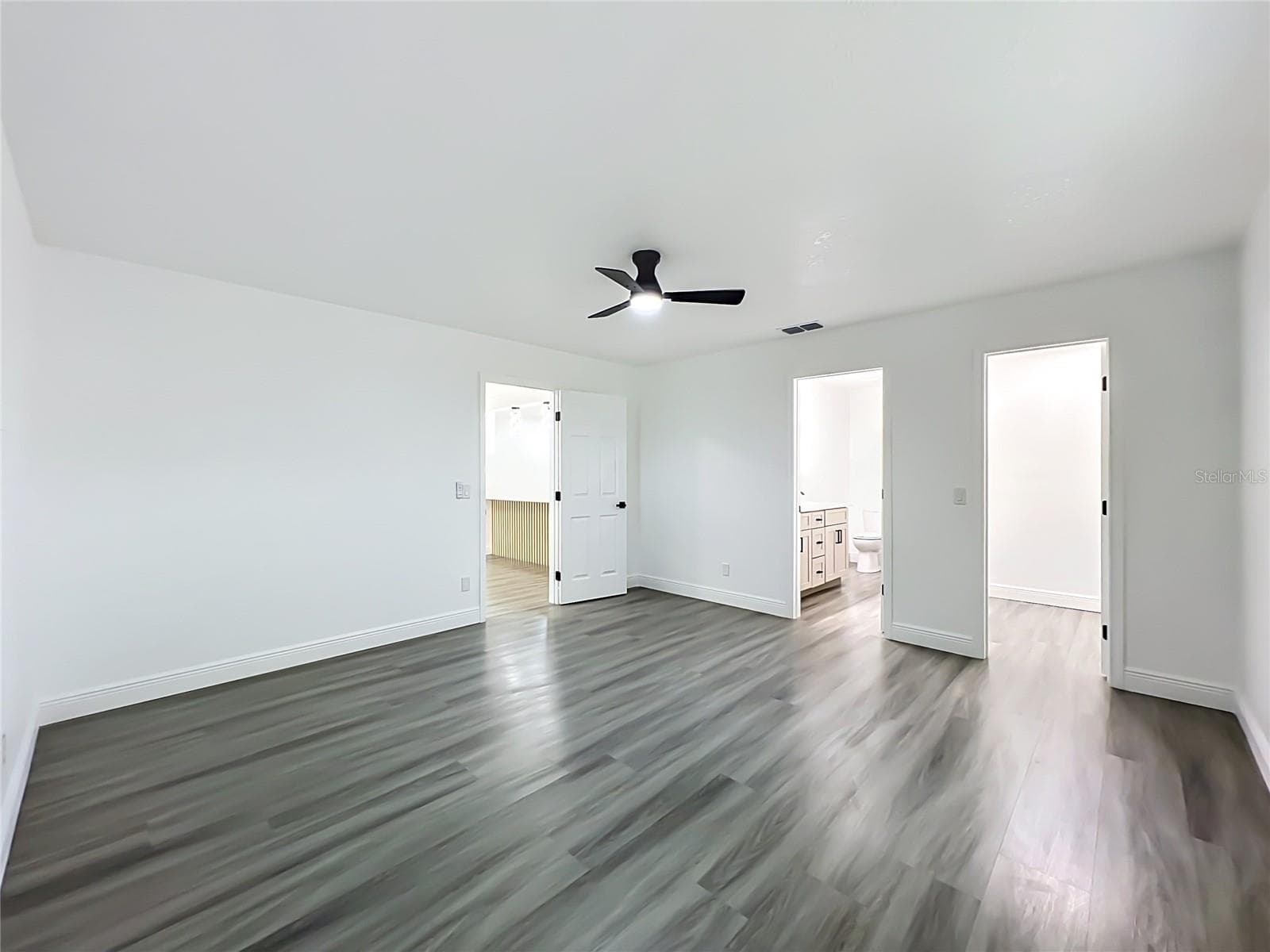 Generously sized primary bedroom with modern flooring and ceiling fan. - 5610 SHASTA DR, ORLANDO