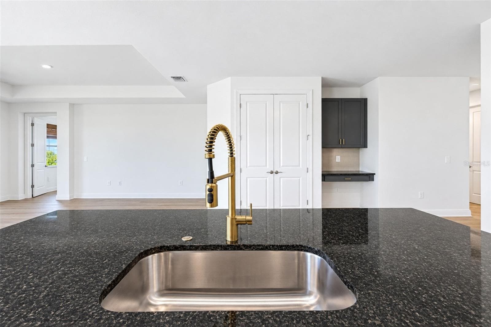 Expansive kitchen island with sleek countertops, undermount sink and statement gold commercial-style faucet, complemented by coordinating gold hardware. - 237 VISTERA BLVD, NOKOMIS