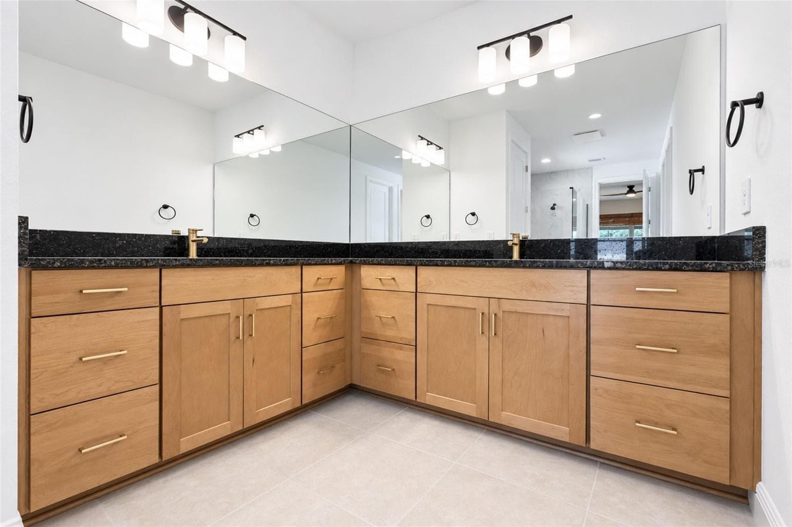 Owner’s suite bath featuring an expansive double vanity with natural wood cabinetry, gold hardware and abundant storage. - 237 VISTERA BLVD, NOKOMIS