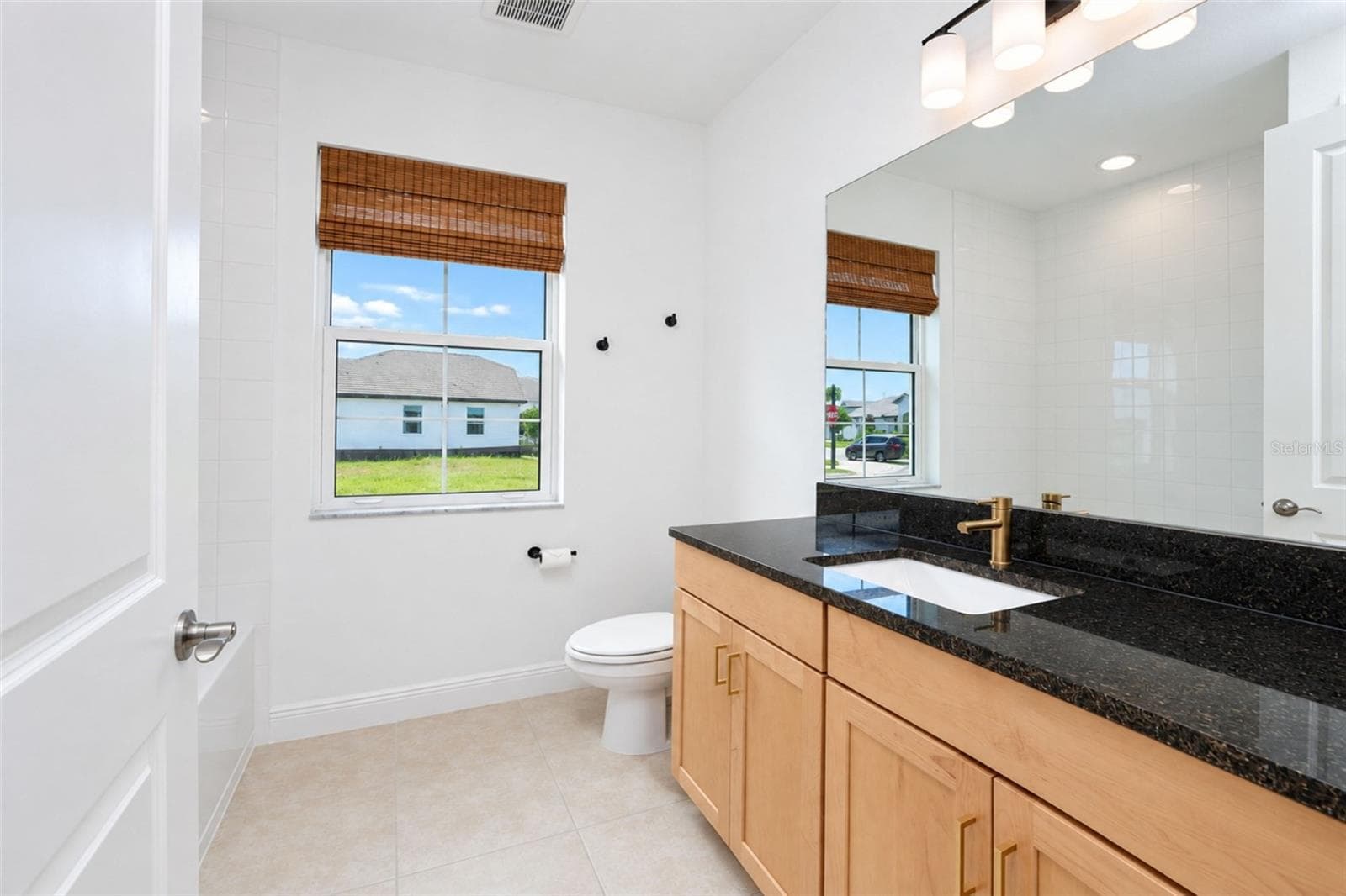Bathroom 2 – Conveniently located between Bedrooms 2 and 3, featuring a tub/shower combination, natural wood vanity, stone countertop and modern black and gold accents. - 237 VISTERA BLVD, NOKOMIS