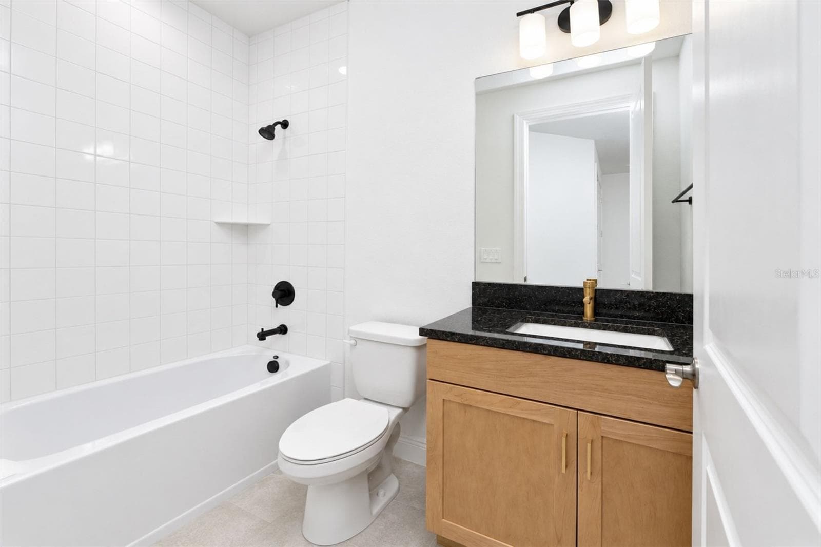 Private en-suite bath # 3 featuring natural wood cabinetry, gold accents, stone countertop and a tiled tub/shower combination with contrasting black fixtures - 237 VISTERA BLVD, NOKOMIS