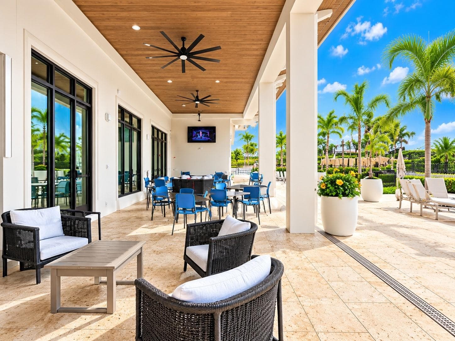 Covered open-air lounge featuring comfortable seating, dining tables, ceiling fans, TVs, and easy access to the resort-style pool area. - 237 VISTERA BLVD, NOKOMIS