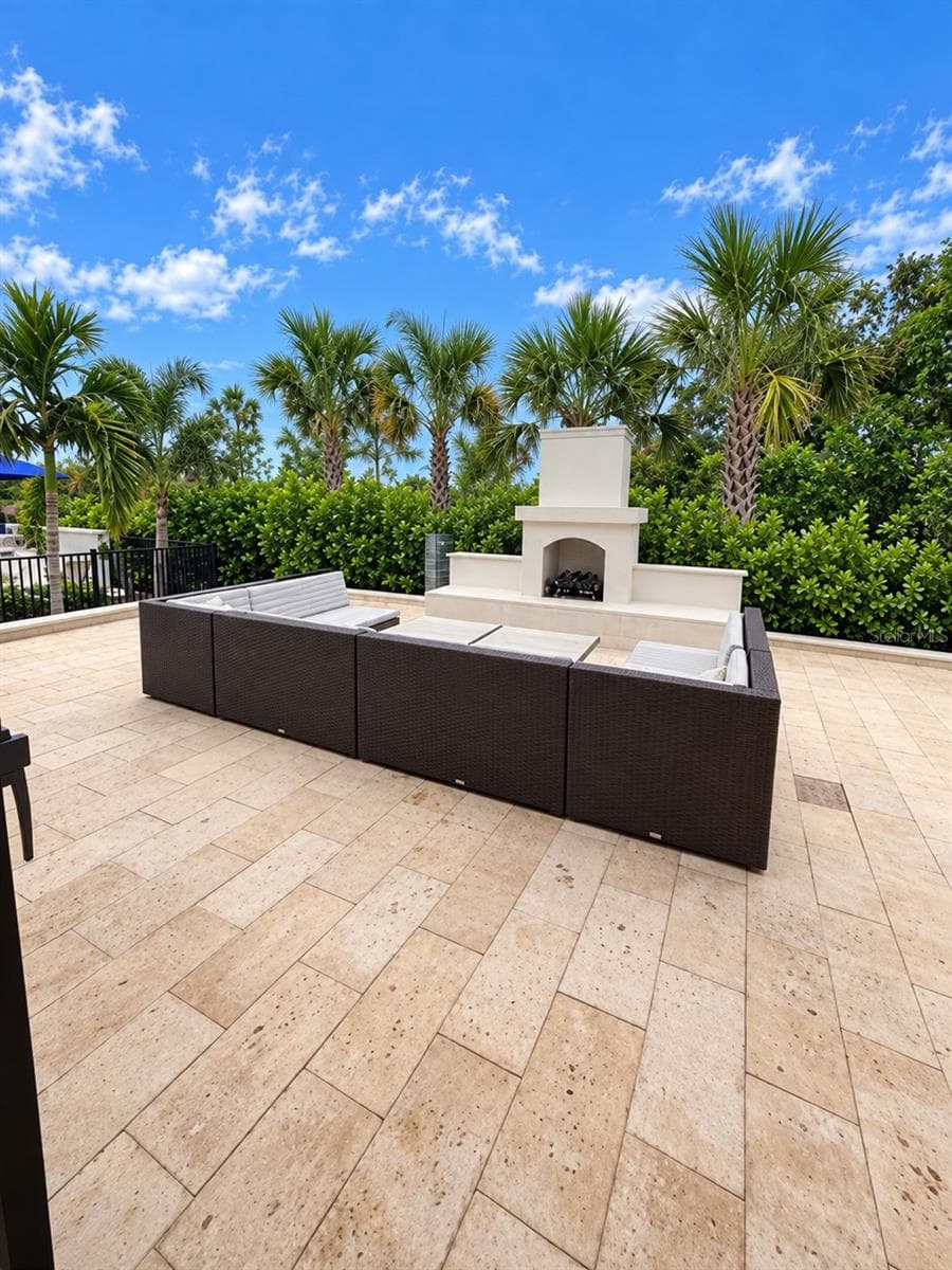 Beautiful travertine patio featuring a fireplace, comfortable lounge seating and lush tropical landscaping—perfect for relaxing and socializing. - 237 VISTERA BLVD, NOKOMIS