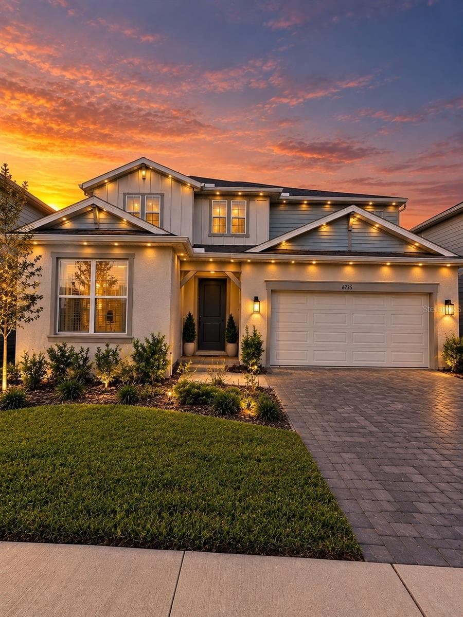 Stunning two-story home featuring beautiful architectural details, elegant exterior lighting, a paver driveway, and exceptional curb appeal. - 6735 REVERIE PARK AVE, ORLANDO