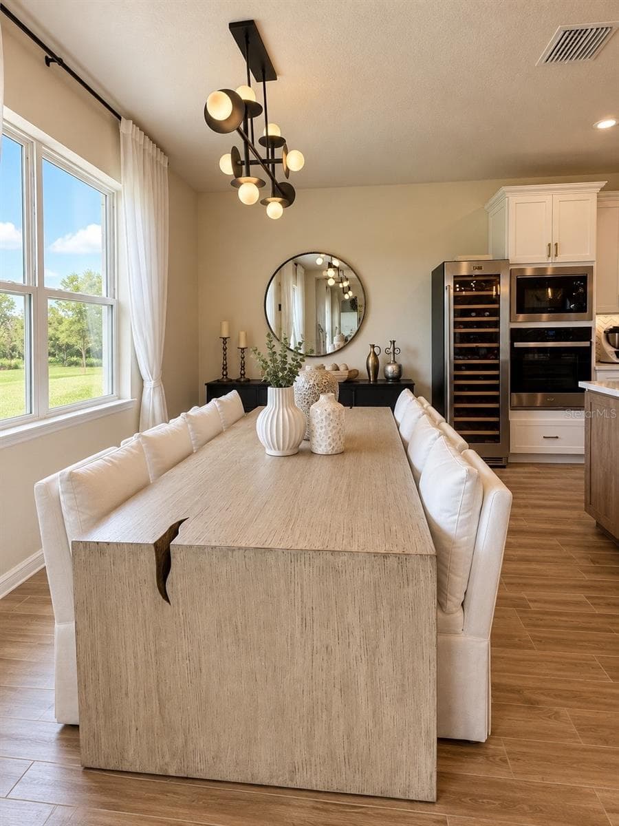 Bright dining area with abundant natural light, modern lighting, and seamless connection to the gourmet kitchen - 6735 REVERIE PARK AVE, ORLANDO