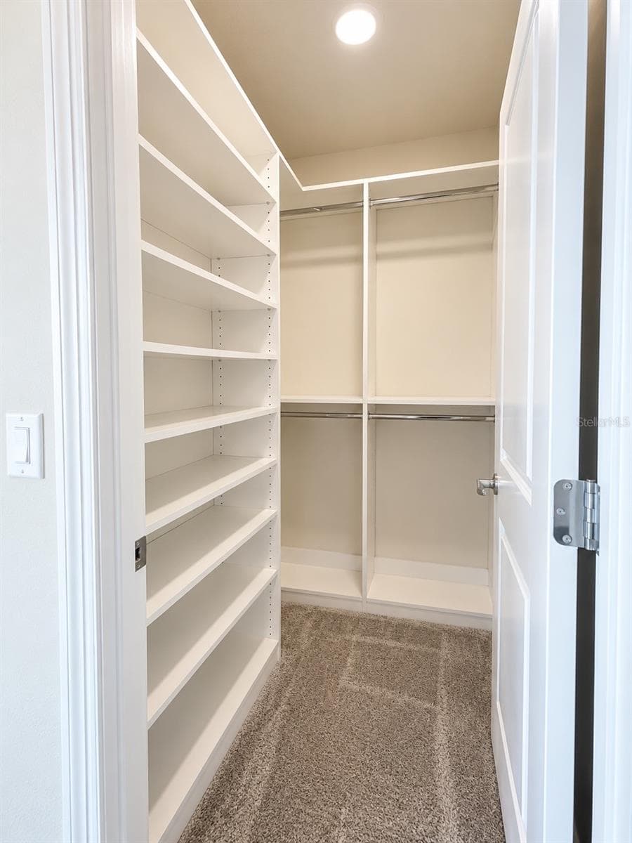 Spacious walk-in closet with custom built-in shelving, double hanging rods, and abundant storage space, conveniently located within the third upstairs suite. - 6735 REVERIE PARK AVE, ORLANDO