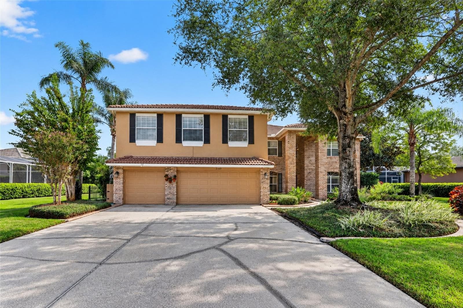 Daylight view of the home and three-car garage. - 2109 WEMBLEY PL, OVIEDO