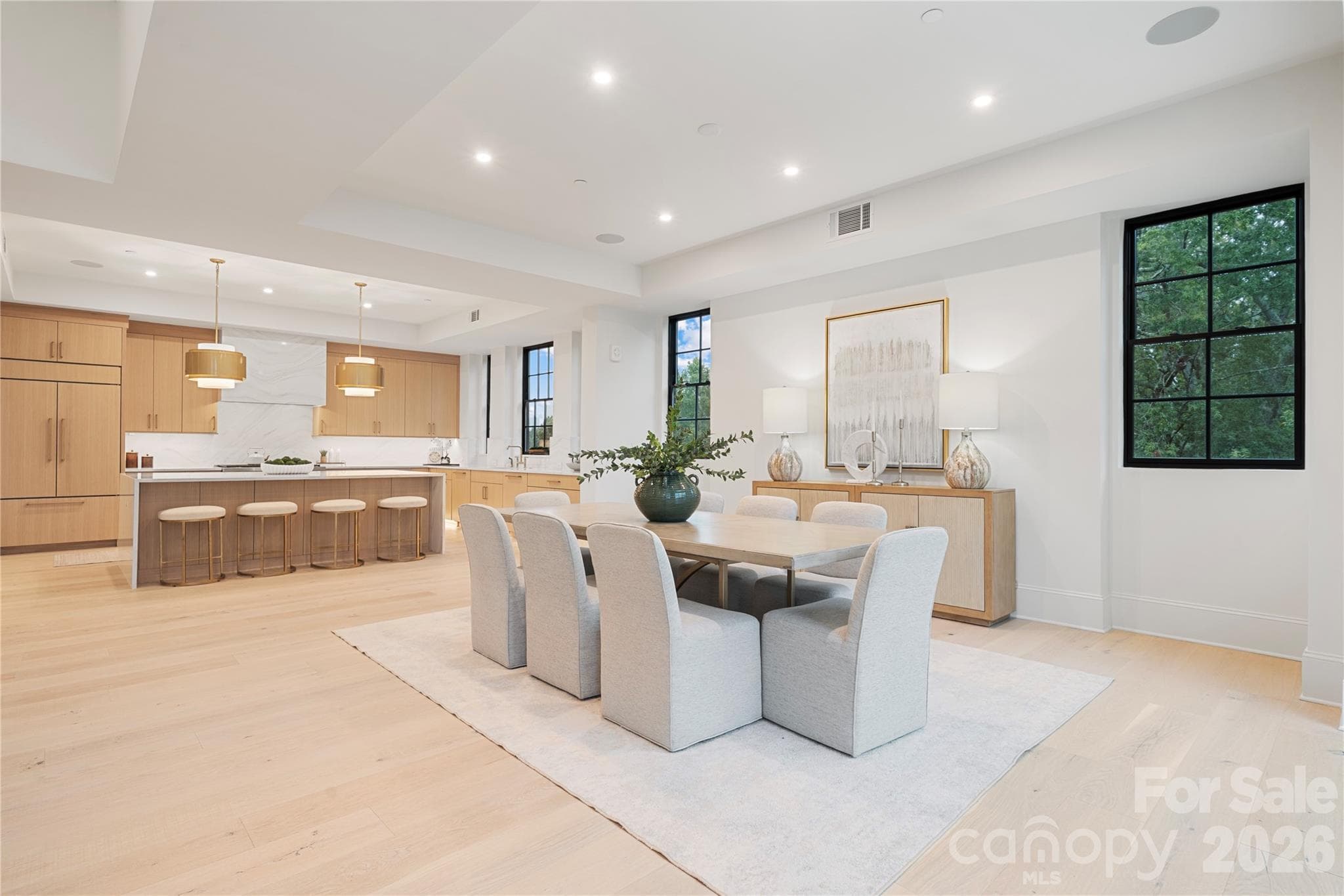 The open sightline and flowing floorplan continue across the dining and kitchen areas. While the light oak cabinetry, wide-plank floors and bright, contemporary design tie it all together beautifully. - 409 Queens Road, Charlotte