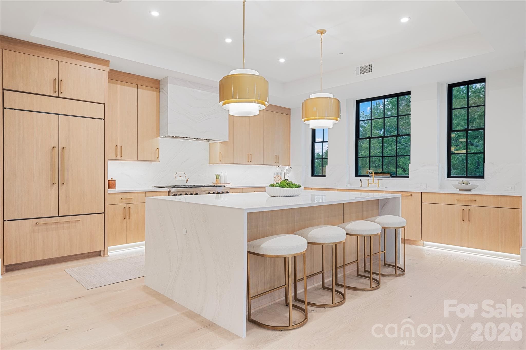 The beautifully designed gourmet kitchen with a extra-wide waterfall-edge island, custom light-wood cabinetry, dramatic stone surfaces and abundant natural light. - 409 Queens Road, Charlotte