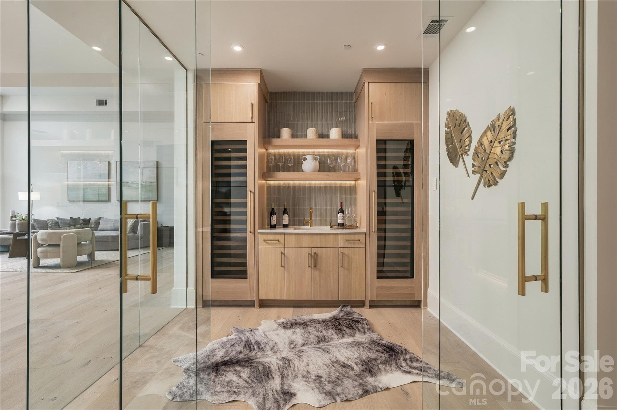 The striking wine room is beautifully finished with glass-enclosure, dual wine refrigerators, custom cabinetry, illuminated shelving and a wet bar for effortless entertaining. - 409 Queens Road, Charlotte