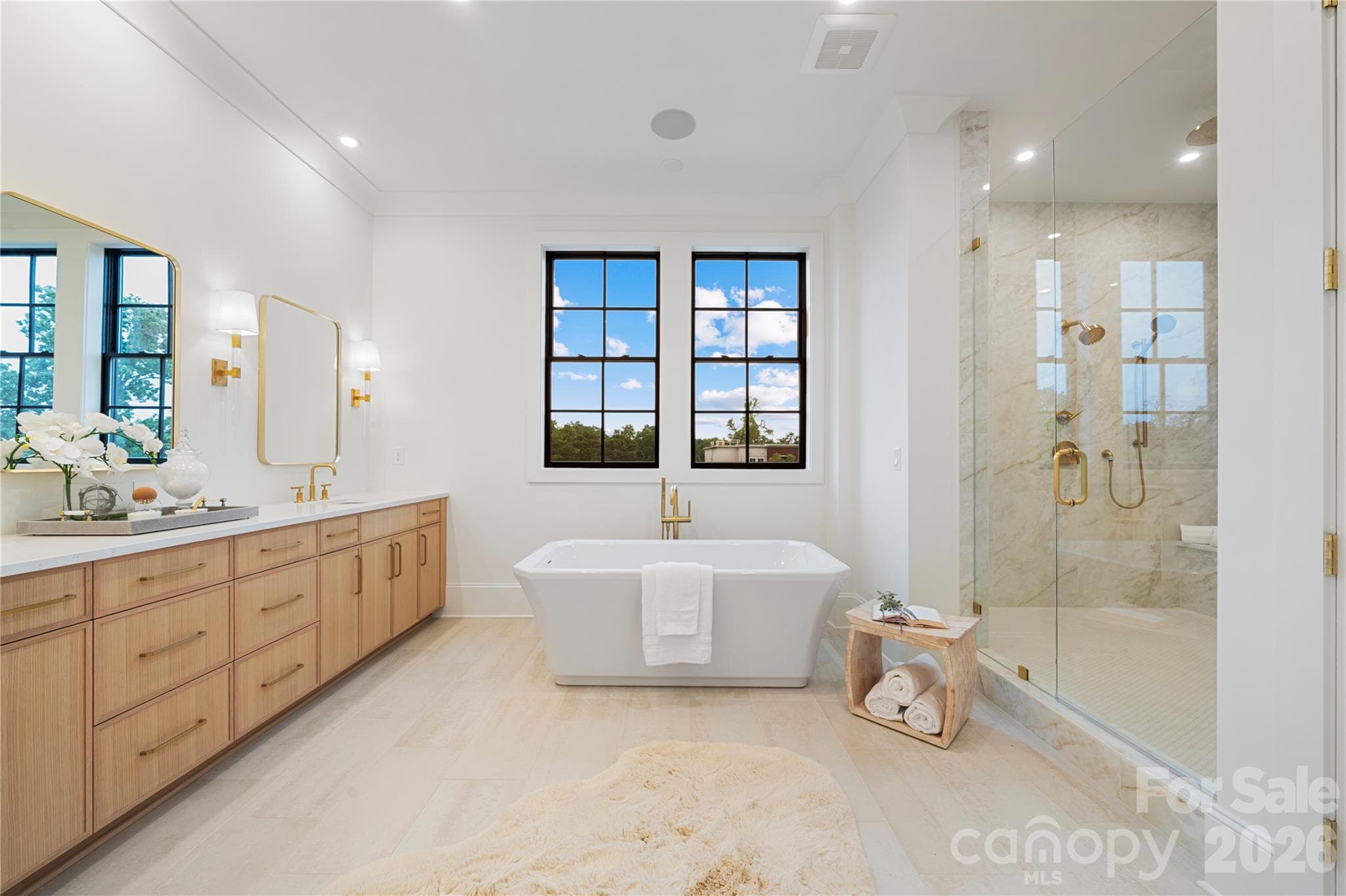 The spa-inspired primary bath provides a freestanding soaking tub, custom dual vanity, natural stone finishes, a goergeous double-wide viewing window and an extraordinary glass-enclosed shower. - 409 Queens Road, Charlotte