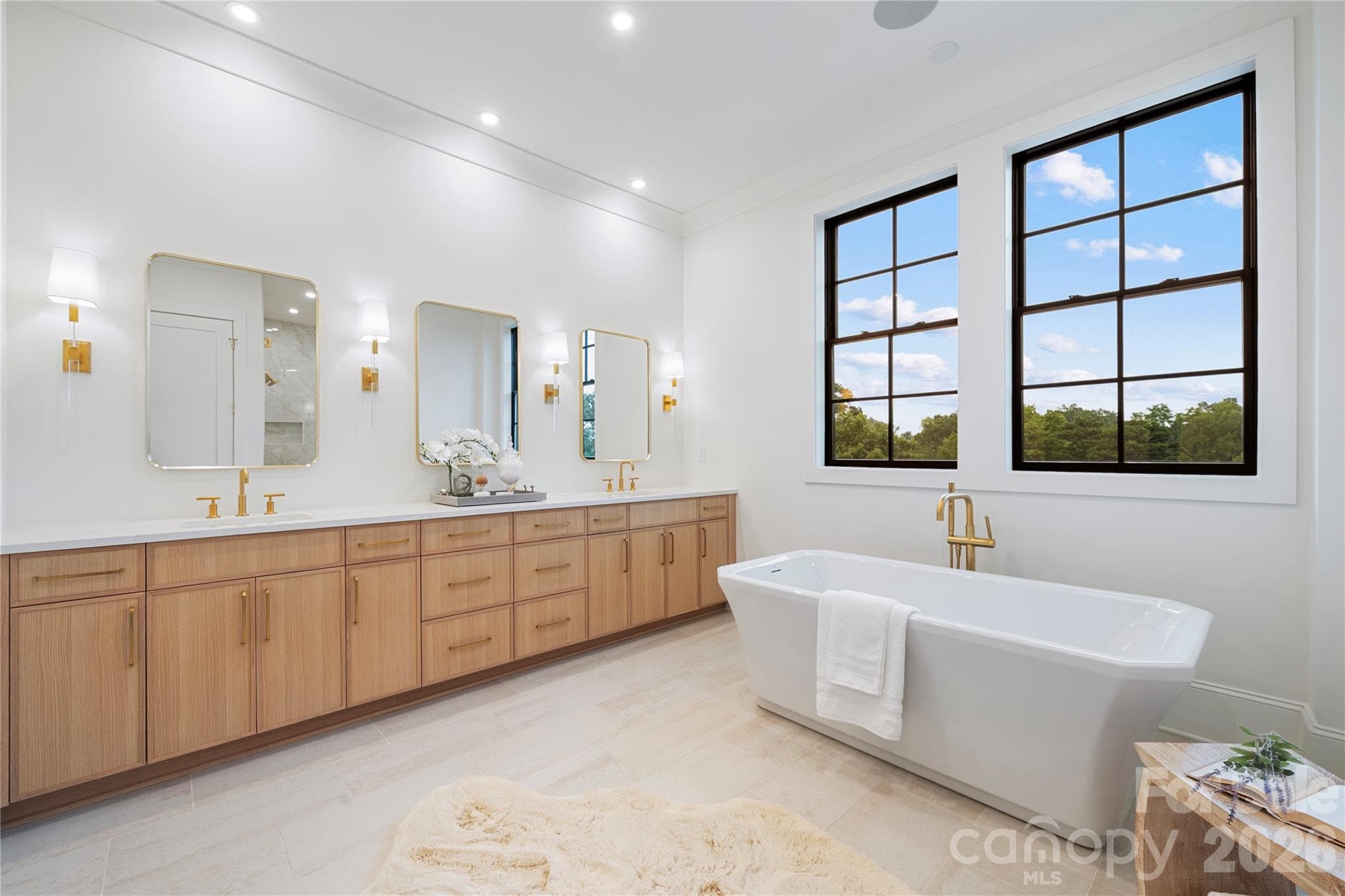 The expansive custom vanity with dual sinks, triplet mirrors and abundant cabinetry ties the room together and fulfills every need for this extraordinary primary bathroom. - 409 Queens Road, Charlotte