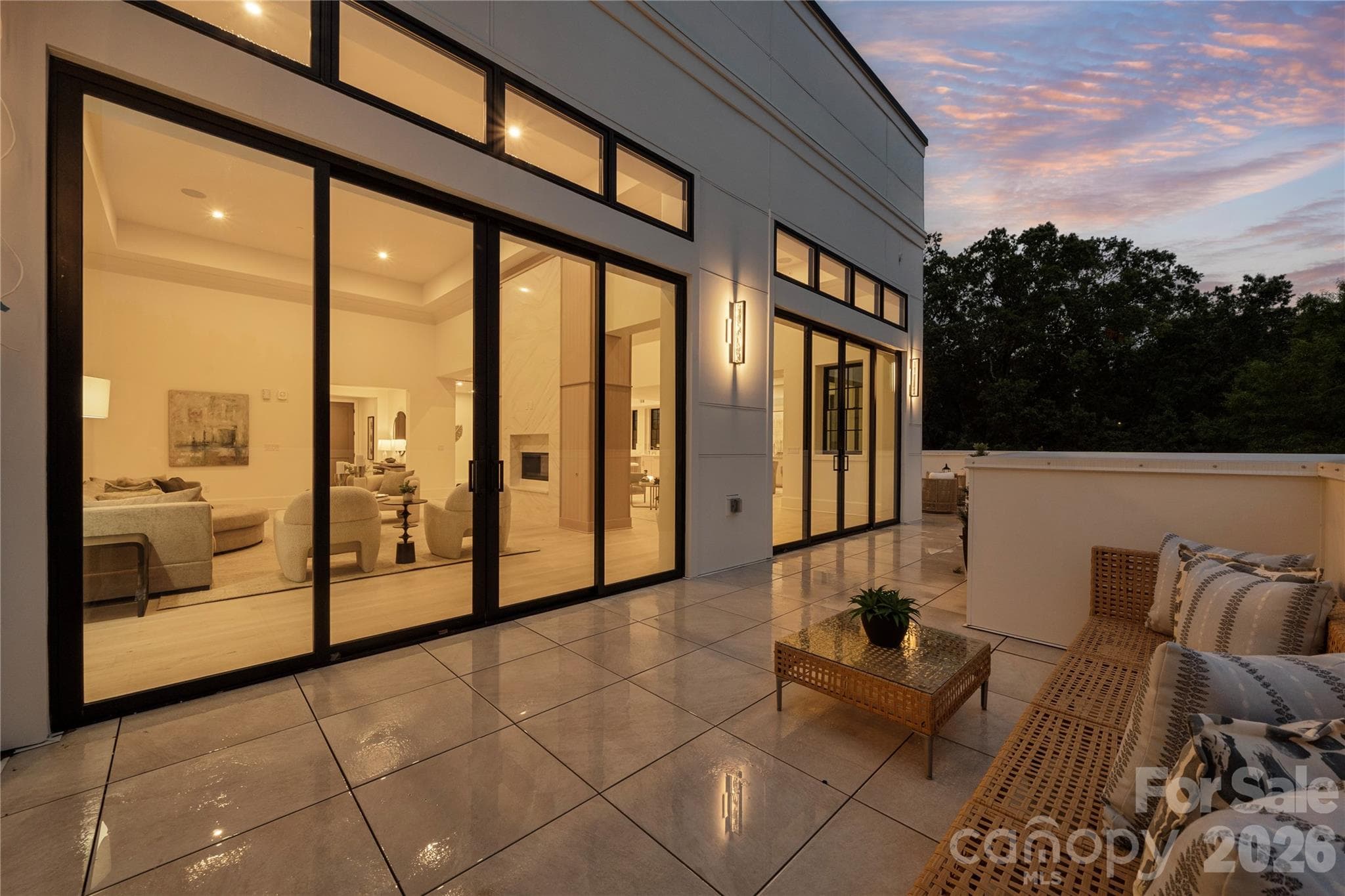 The expansive terrace with walls of glass opening to the illuminated living spaces, creates a seamless indoor-outdoor setting that is unique in Charlotte and perfect for relaxing evenings and entertaining. - 409 Queens Road, Charlotte