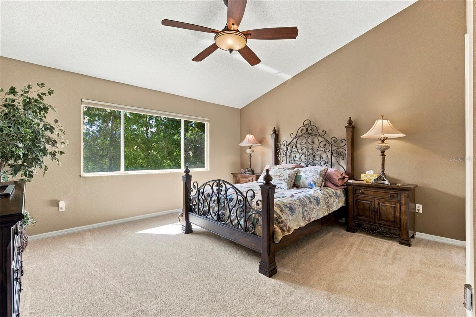 Primary bedroom with vaulted ceiling and peaceful view of the pond and trees - 11193 KAPOK GRAND CIR, SEMINOLE