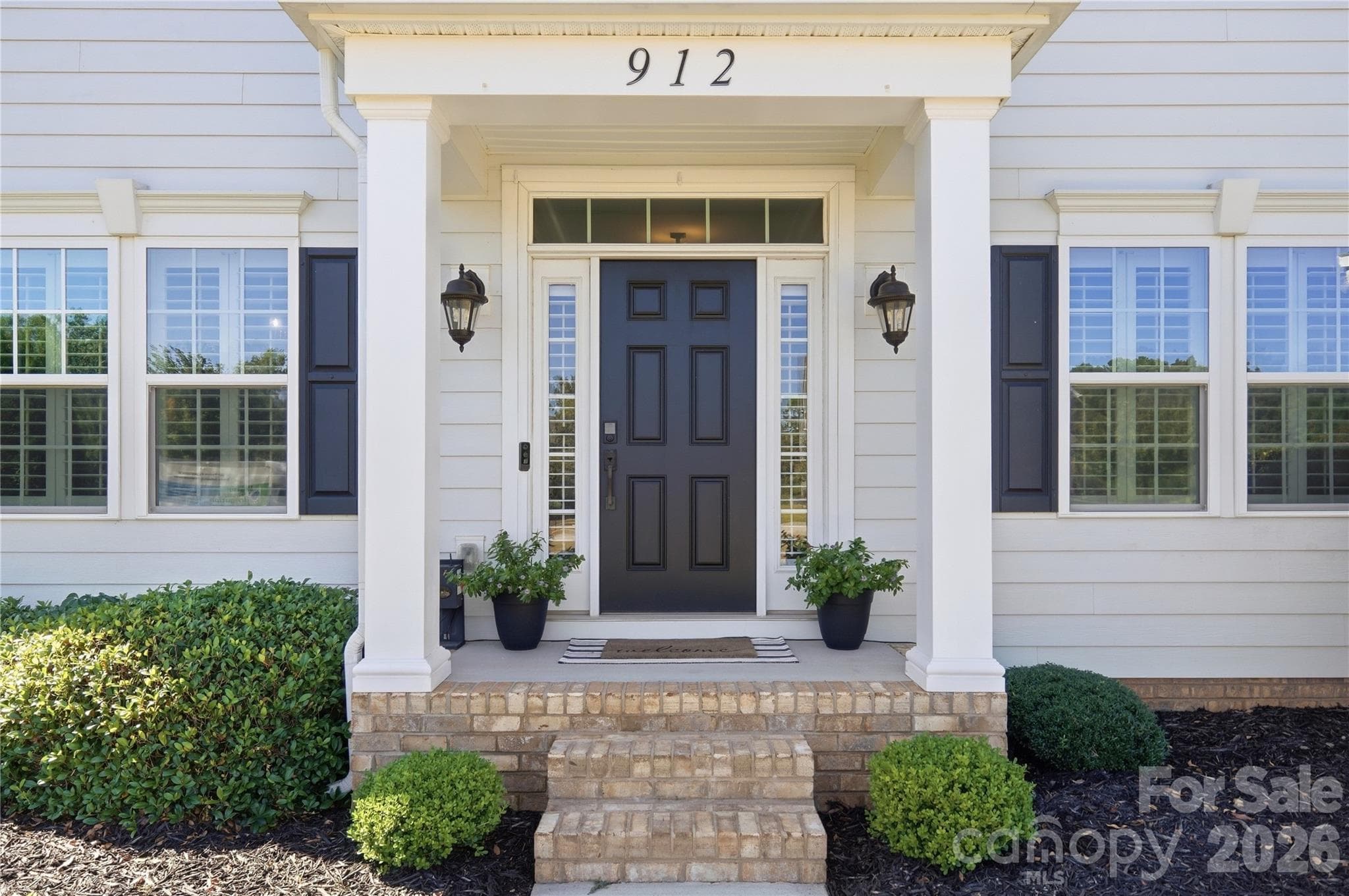 Classic two-story Colonial with triple dormers, shutters, a columned front portico, and mature landscaping. - 912 Manorwood Drive, Waxhaw