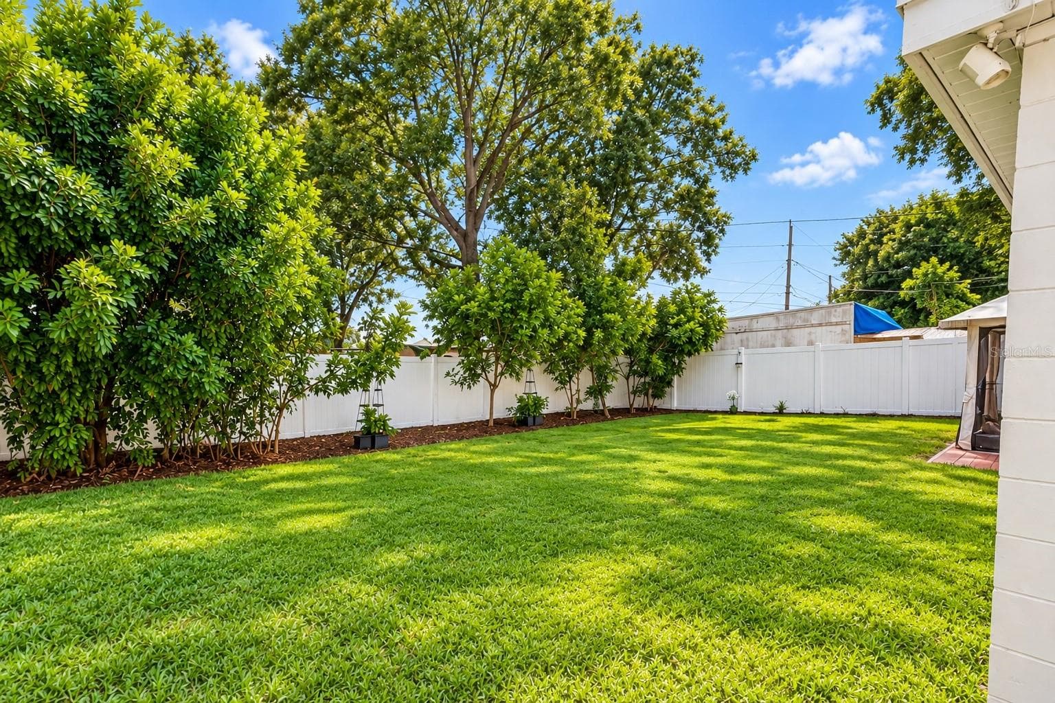 Large private backyard surrounded by white vinyl privacy fencing. - 8514 93RD AVE, SEMINOLE