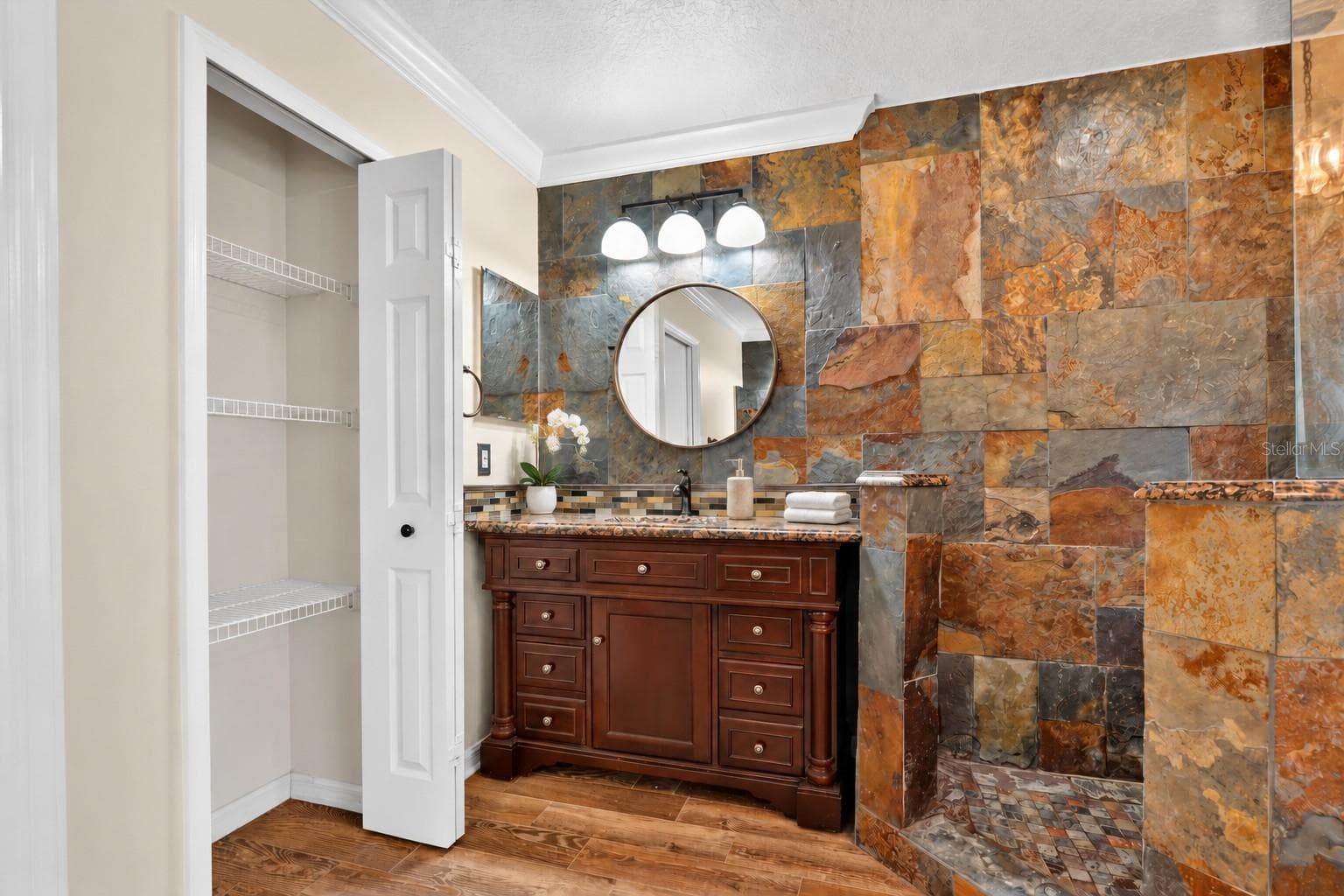 Primary bathroom vanity with decorative tile and a round mirror. - 2109 WEMBLEY PL, OVIEDO