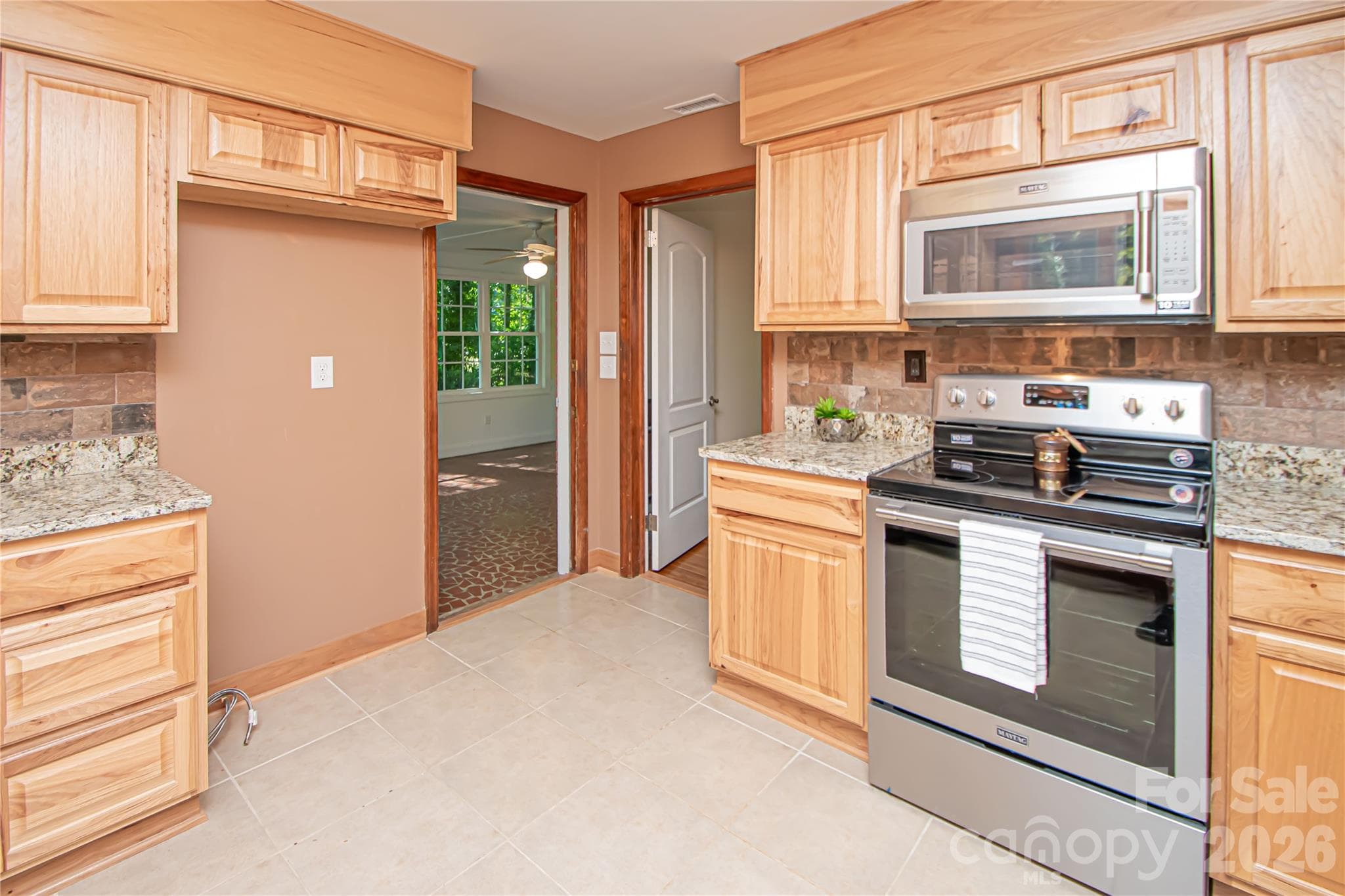 Kitchen was updated a few years ago with stainless steel appliances, new cabinets, tile backsplash, tile floor and granite countertops. - 7400 Oakwood Lane, Charlotte