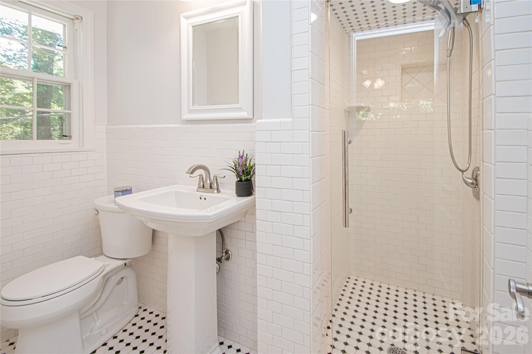 Primary bathroom has been updated with new tile, seamless shower, new hardware, pedestal sink with faucet. - 7400 Oakwood Lane, Charlotte