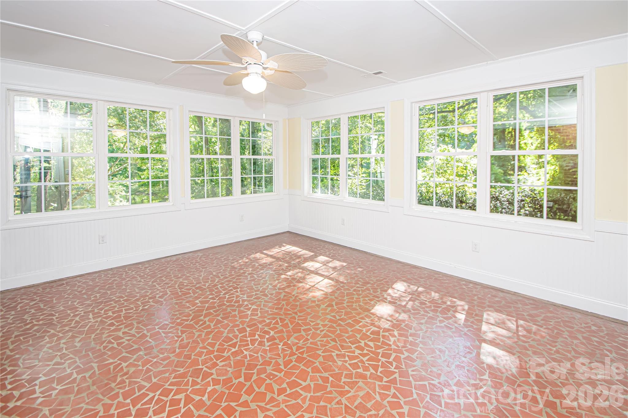 Spacious sunroom has windows all over that provide beautiful views of the lake.  Photo has been enhanced by AI to show placement of furniture. - 7400 Oakwood Lane, Charlotte