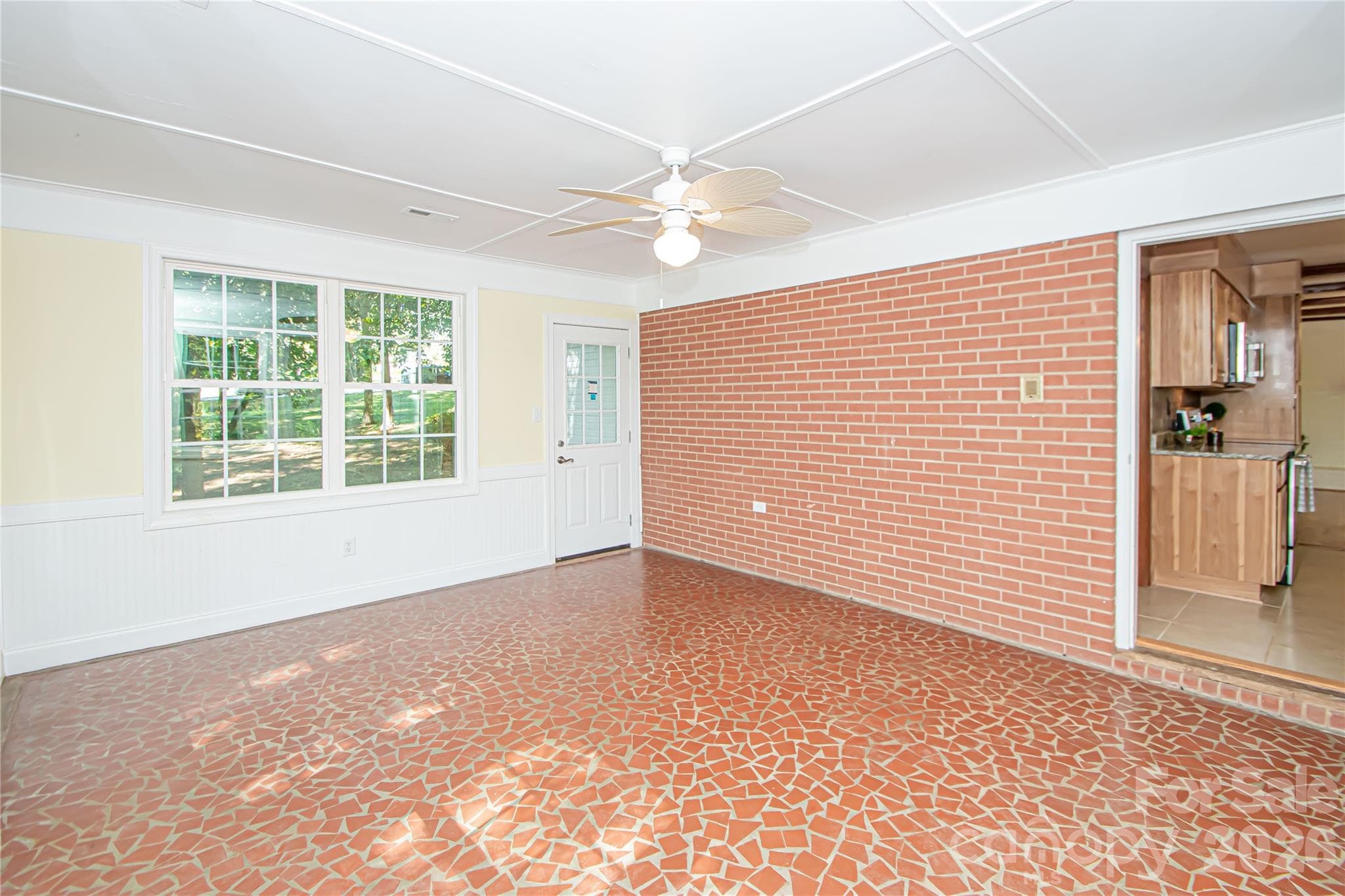 Spacious sunroom has windows all over that provide beautiful views of the lake.  Photo has been enhanced by AI to show placement of furniture. - 7400 Oakwood Lane, Charlotte
