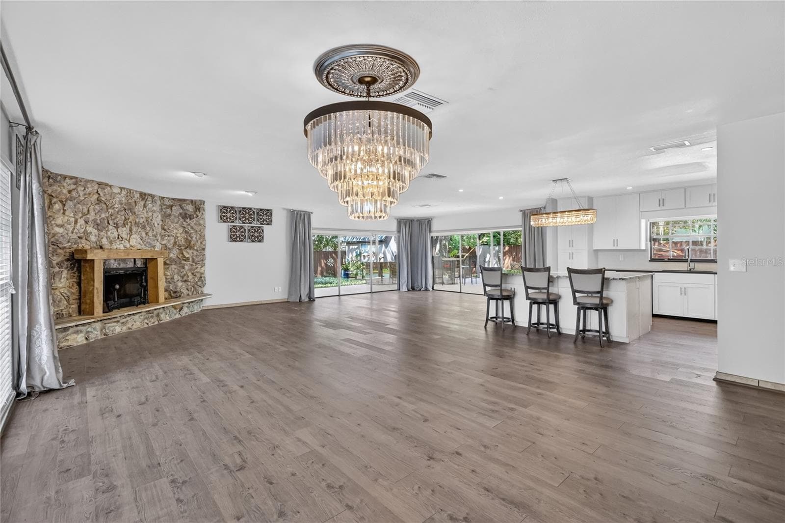 An open-concept layout is anchored by a striking floor-to-ceiling stone fireplace and wide plank wood-look flooring. - 3011 LAKE ELLEN DR, TAMPA