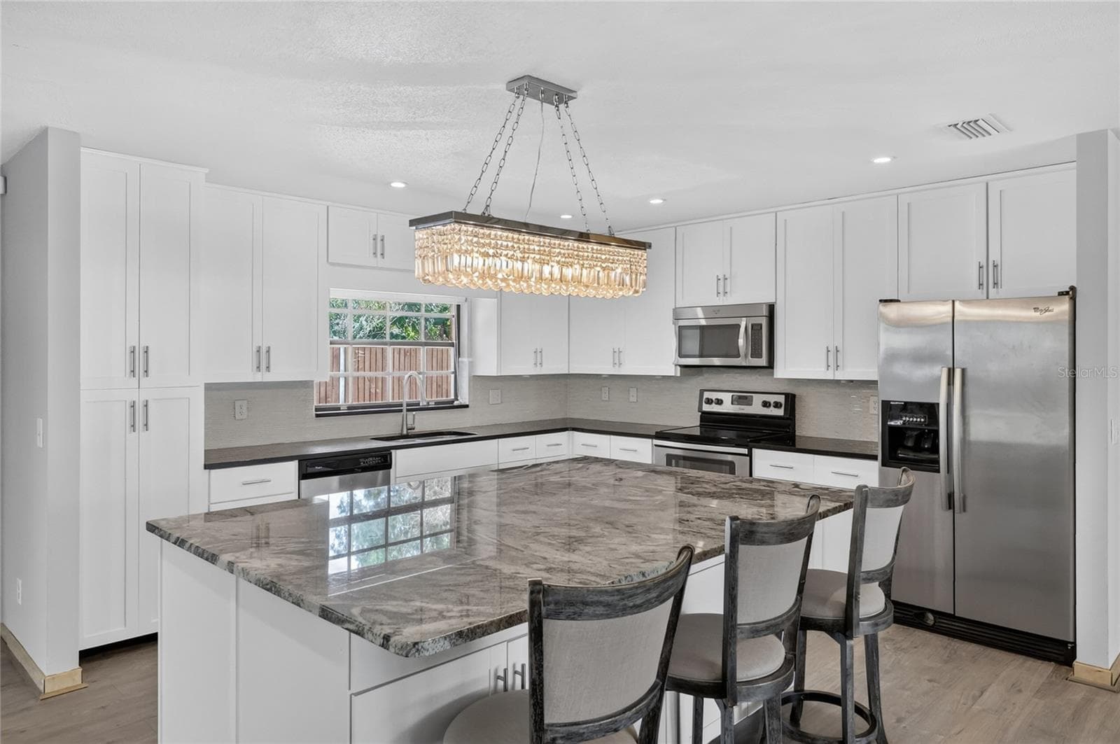 Fully Renovated Kitchen is a true centerpiece, featuring crisp white cabinetry, granite countertops, a massive center island, stainless steel appliances, and designer lighting. - 3011 LAKE ELLEN DR, TAMPA