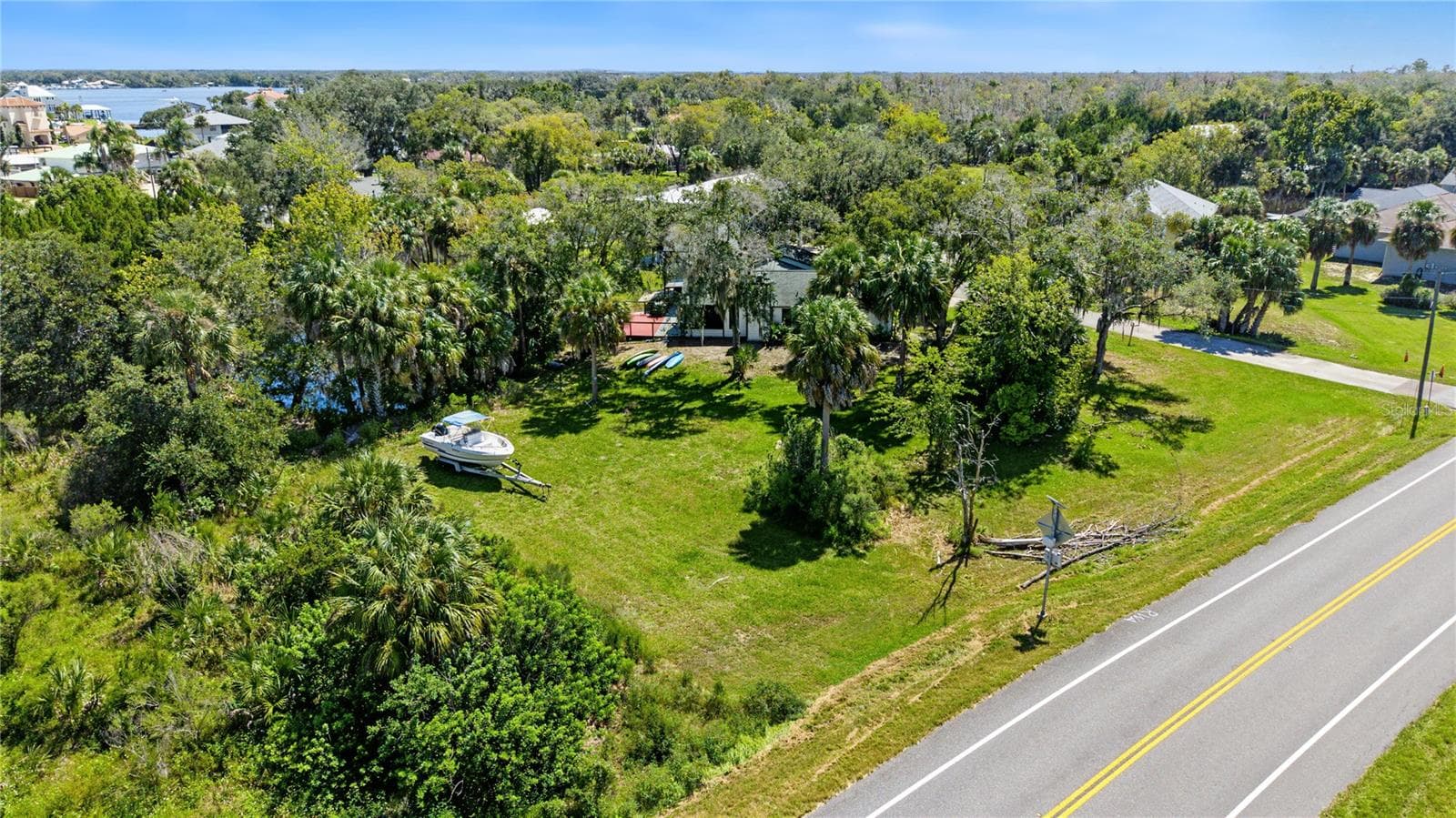 Wide aerial view showcasing the property's natural surroundings and nearby road access. - 10933 W FORT ISLAND TRL, CRYSTAL RIVER