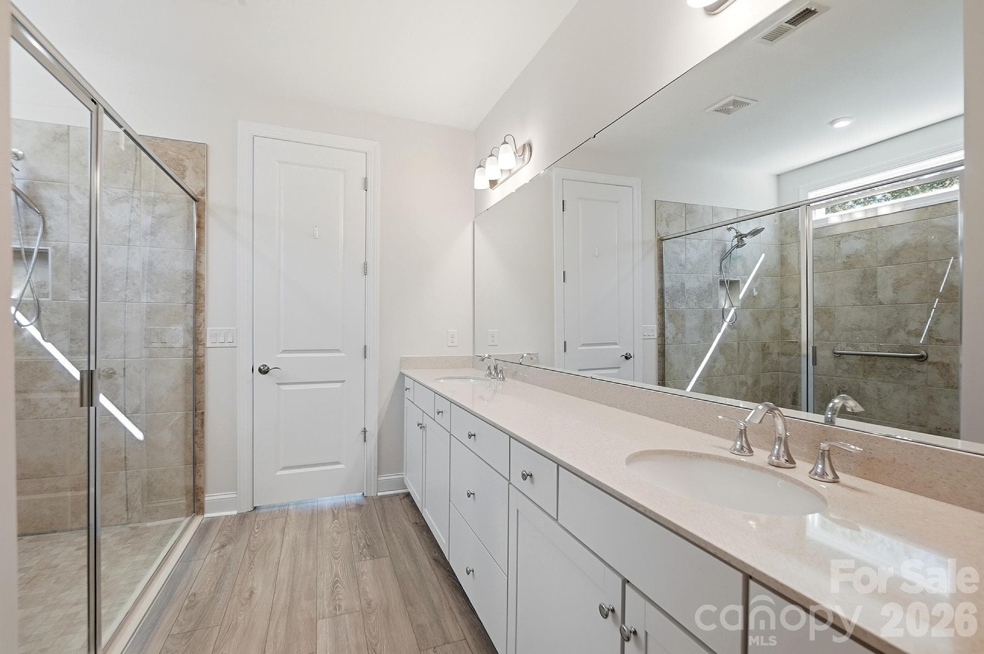 Luxurious primary bath offers dual vanities, an oversized walk-in tile shower with handicap grab bar, and a large walk-in closet - 8032 Longwaters Court, York