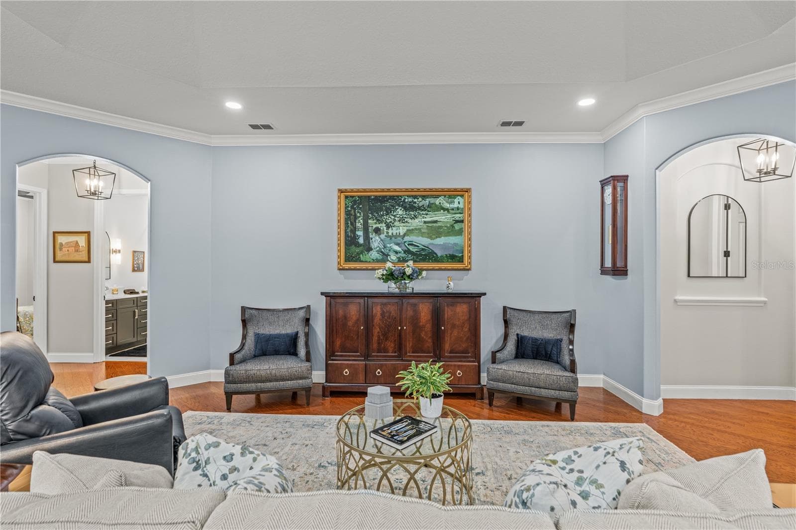 The "painting" over the cabinet is actually the TV!  The arched hallway to the right leads to the primary suite and the arched hallway to the left takes you to the 2 guest rooms and laundry room - 520 SOTHEBY WAY, DEBARY