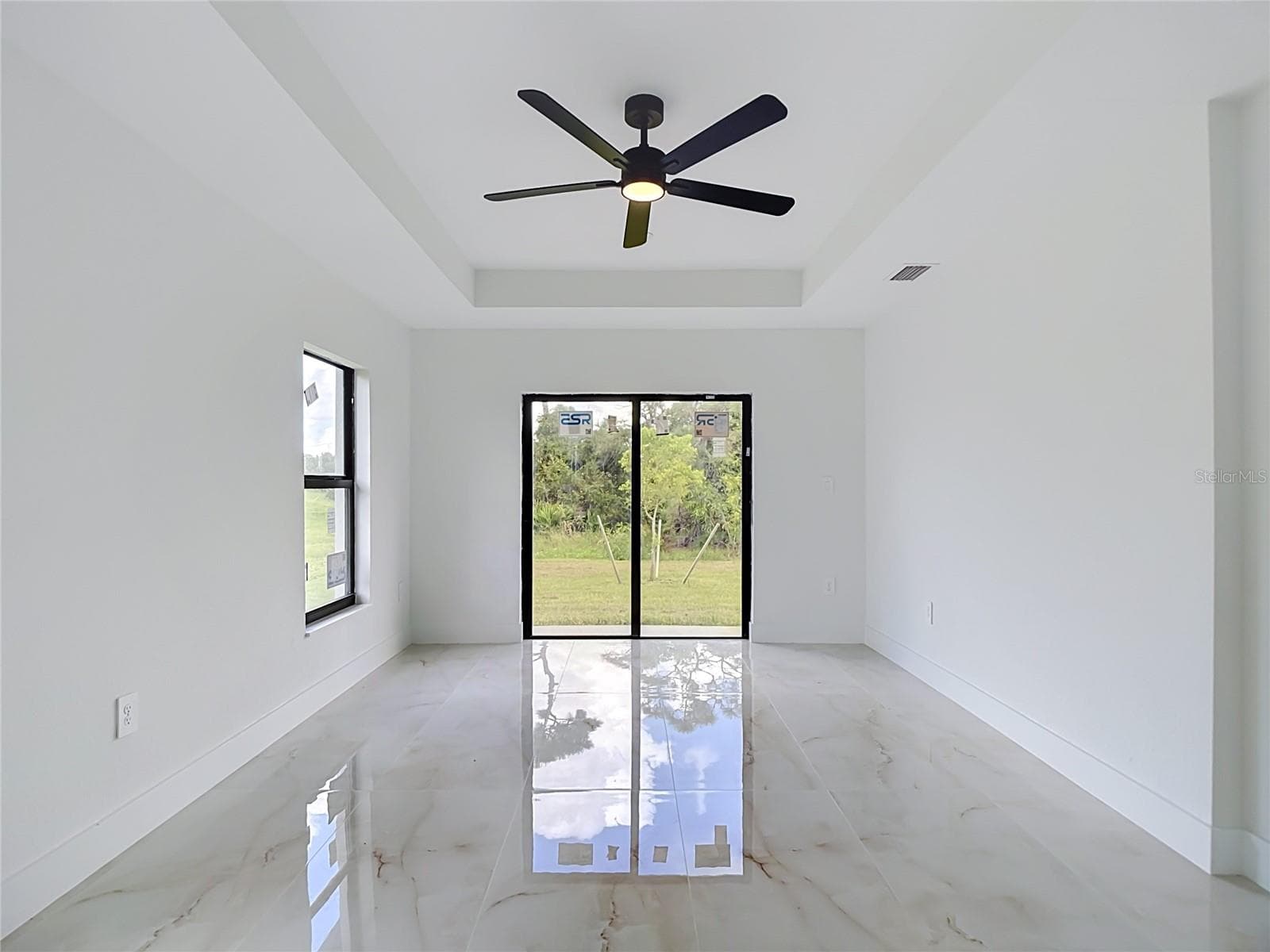 Primary bedroom with tray ceiling, ensuite bathroom, walk in closet and sliding doors to backyard - 3613 NW 47TH LN, CAPE CORAL