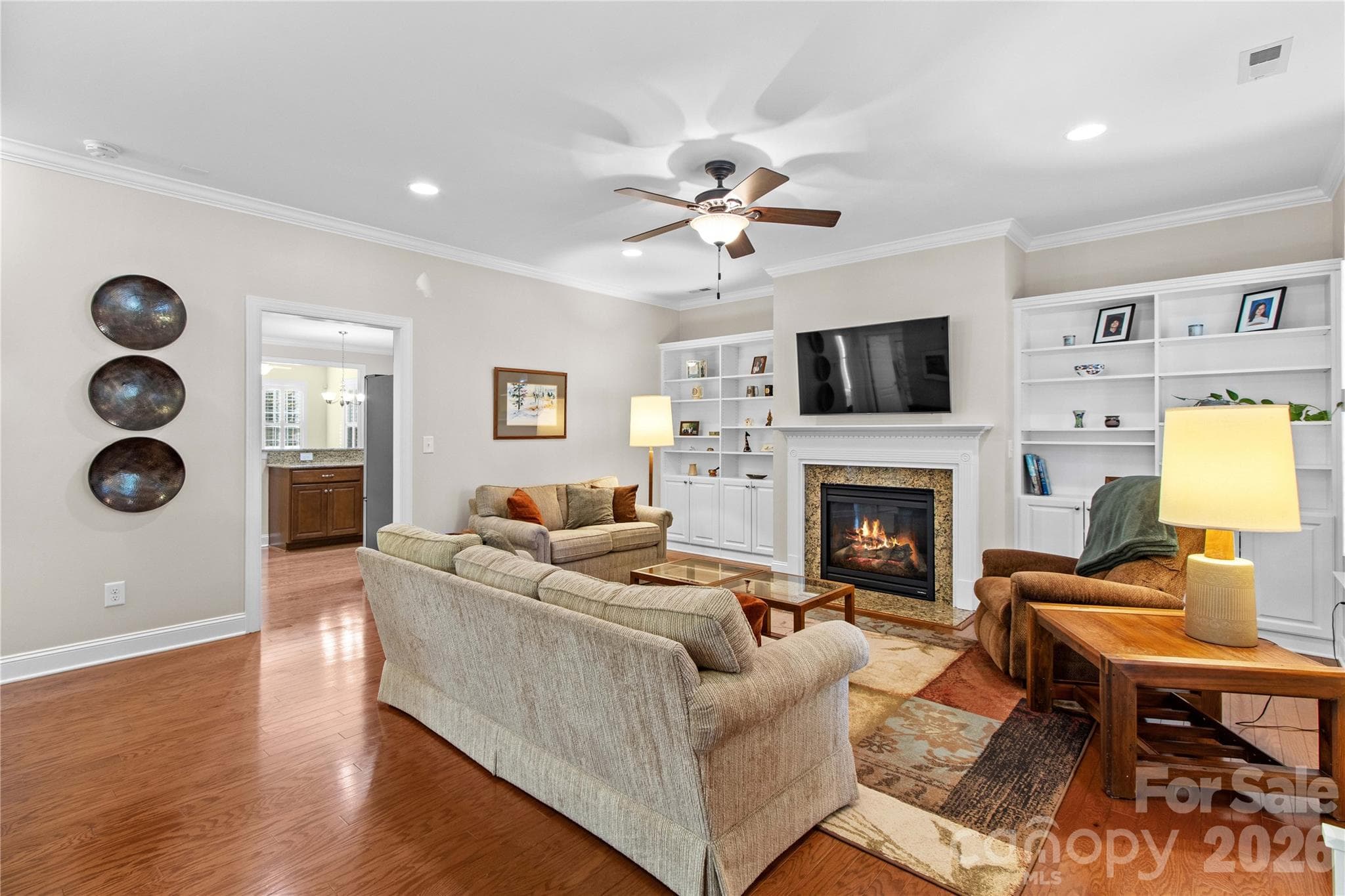The livng room showcases gleaming hardwood floors and is anchored by a gas fireplace flanked by custom built—ins. - 18114 Ebenezer Drive, Cornelius