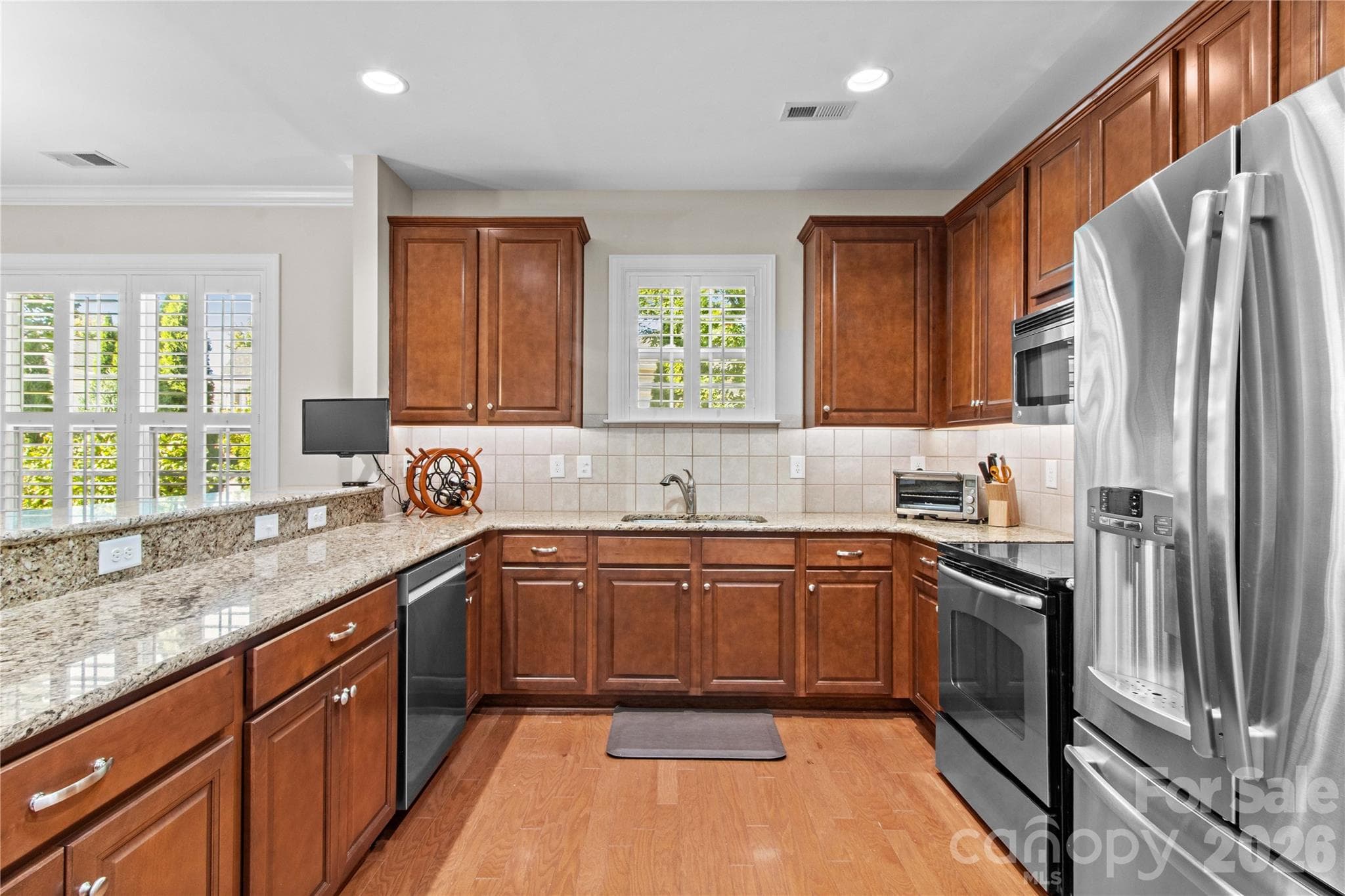 Oversized kitchen with tons of cabinet and counter space, undercabinet lighting, granite counters, tile backsplash, stainless appliance, and a solar tube allowing natural light. - 18114 Ebenezer Drive, Cornelius