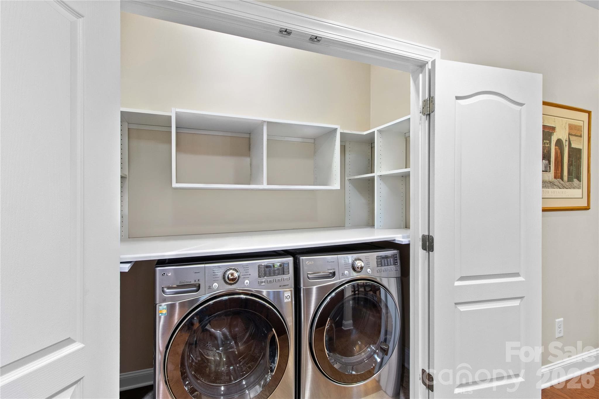 Laundry closet has custom wood shelving which provides extra storage and a place for folding clothes. - 18114 Ebenezer Drive, Cornelius