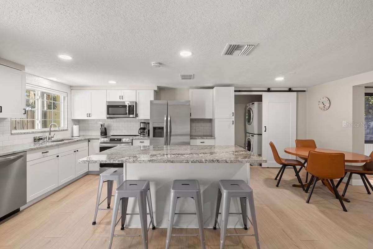 Another view highlights the generous island, open dining area, and convenient tucked-away laundry—all seamlessly connected to the main living spaces. - 201 SOUTH ST, PALM HARBOR