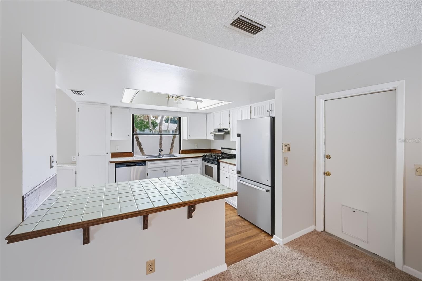 View into the kitchen from the dinette area/small breakfast bar. Garage door to the right with doggie door - 83 FARRAGUT DR, PALM COAST