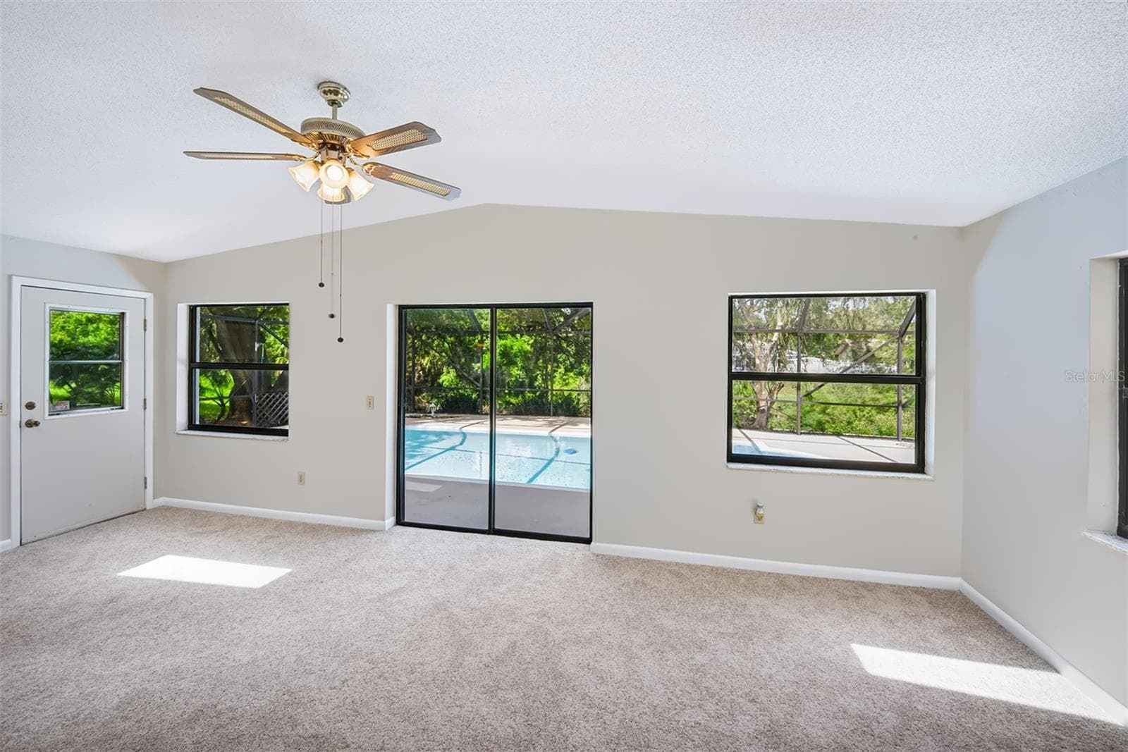 Florida room with side door and sliding glass doors out to the enclosed lanai/pool area - 83 FARRAGUT DR, PALM COAST