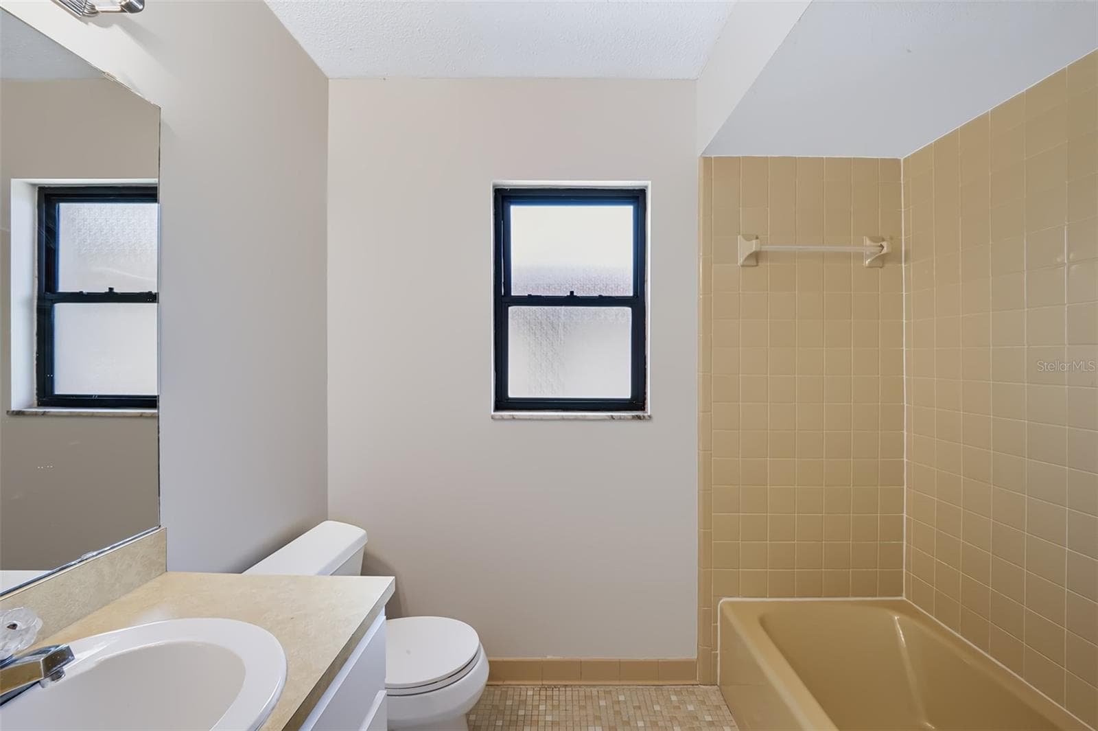 Secondary bathroom conveniently located in hall between both bedrooms. This bathroom also features retro-style glazed ceramic tile, it has a linen closet to the left of the sink with built-in medicine cabinet on wall, and has a tub/shower combination - 83 FARRAGUT DR, PALM COAST
